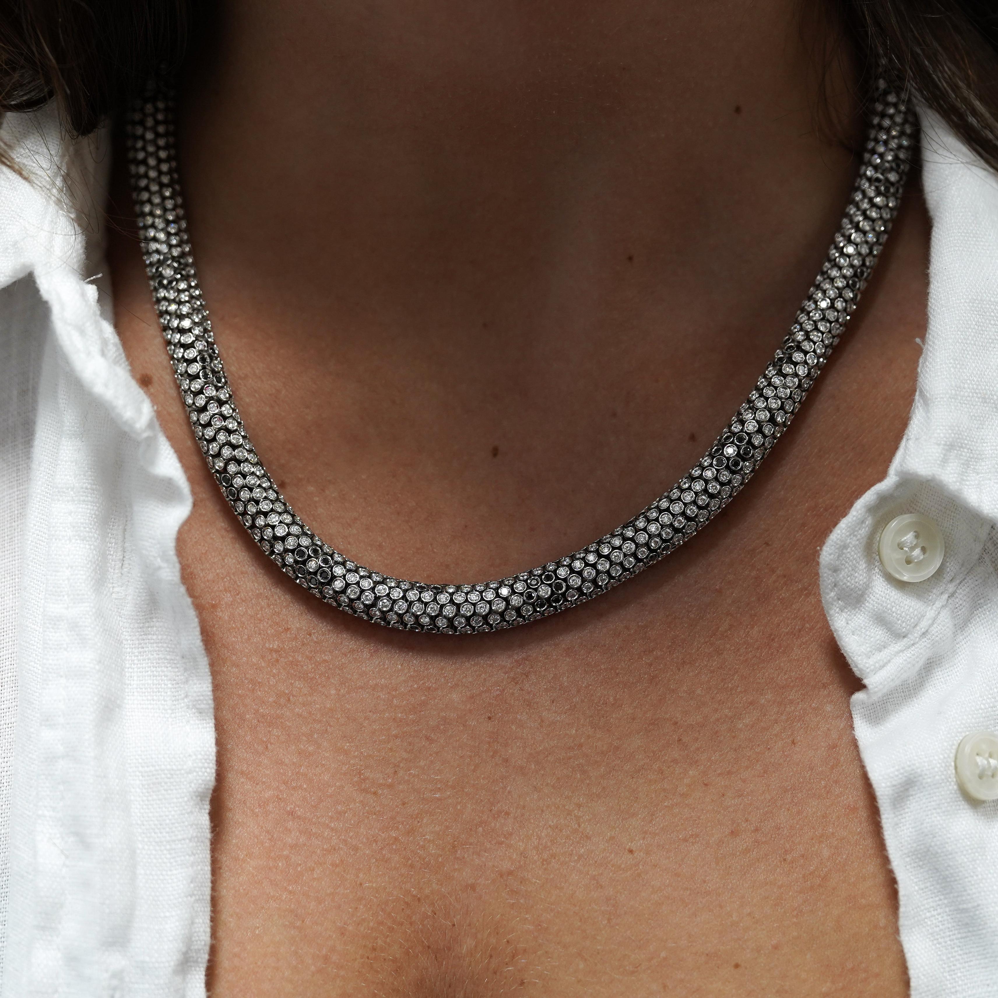 Ce collier de diamants ondulé de forme cylindrique en or blanc 18 carats présente 50 carats de diamants ronds de taille brillant avec des diamants noirs de taille unique formant une fleur tout au long du collier. Cette pièce est extrêmement bien