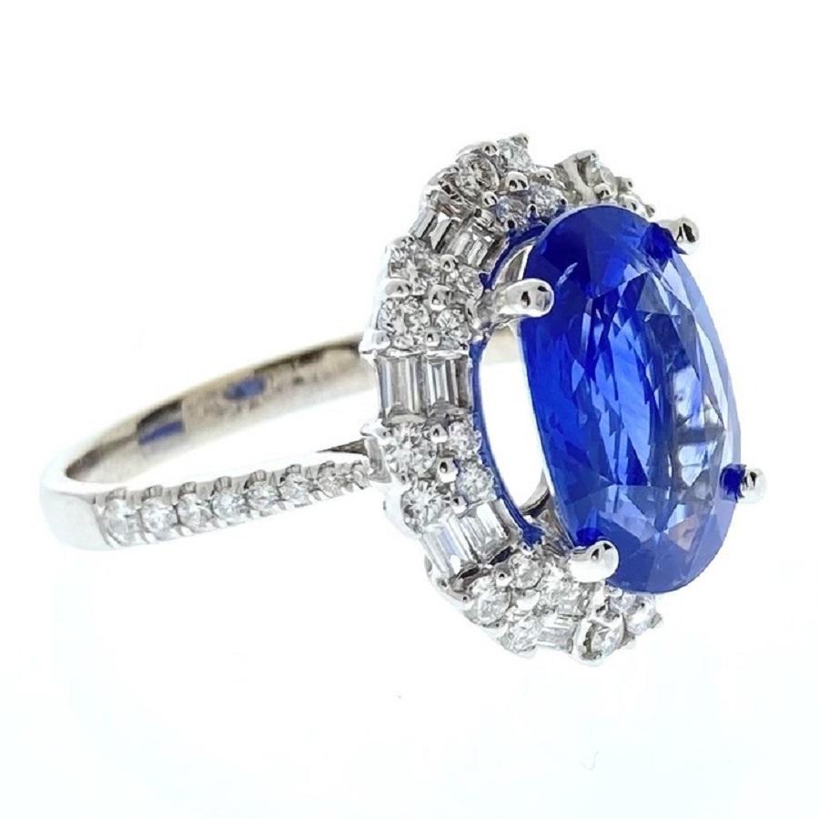 This exquisite ring features a stunning 5-carat blue oval sapphire, renowned for its deep, vibrant hue and captivating brilliance. The sapphire is elegantly set in a classic 18k white gold band, which complements its rich color with a sleek,
