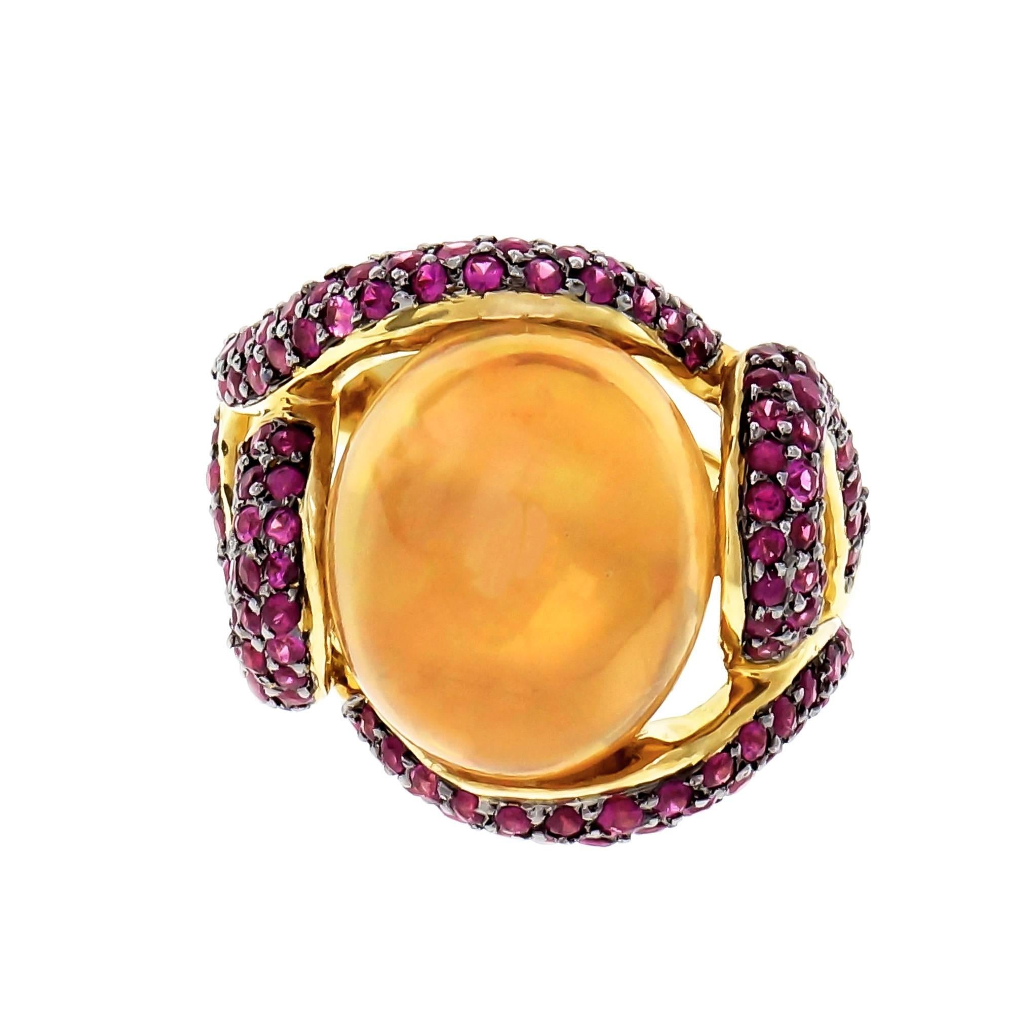 Designer Dyach Opal and ruby cocktail ring. 18k yellow gold free form swirl ring set with a natural Mexican fine Opal approx. total weight 5.00cts in a golden orange color with red green and blue flash with Pavé set with of bright red Rubies.

1