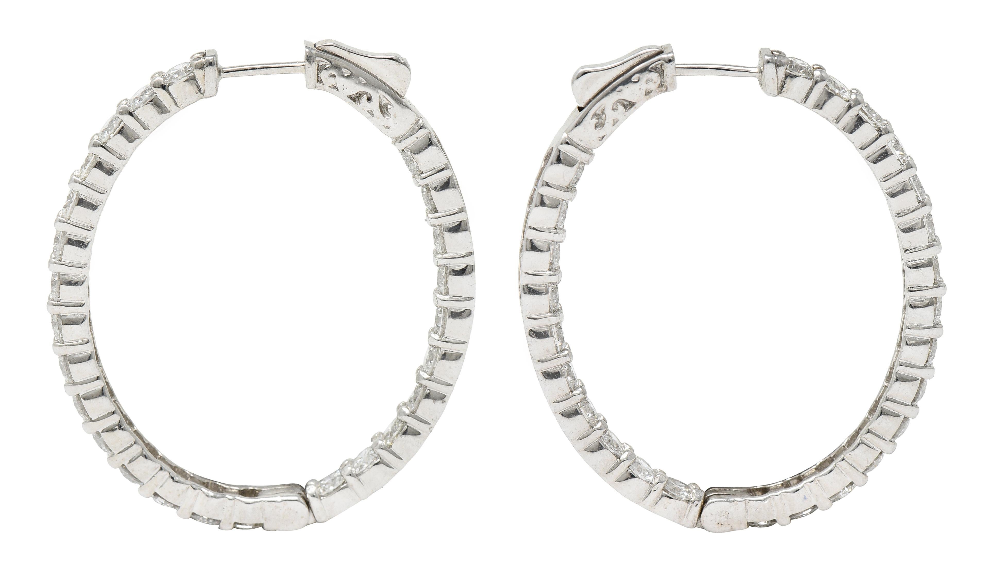 Inside/outside style oval shaped huggie hoop earrings

With shared prong round brilliant cut diamonds

Weighing in total approximately 5.04 carats - G/H color with overall VS clarity

Opens on a hinge via presser revealing posts

Inscribed with