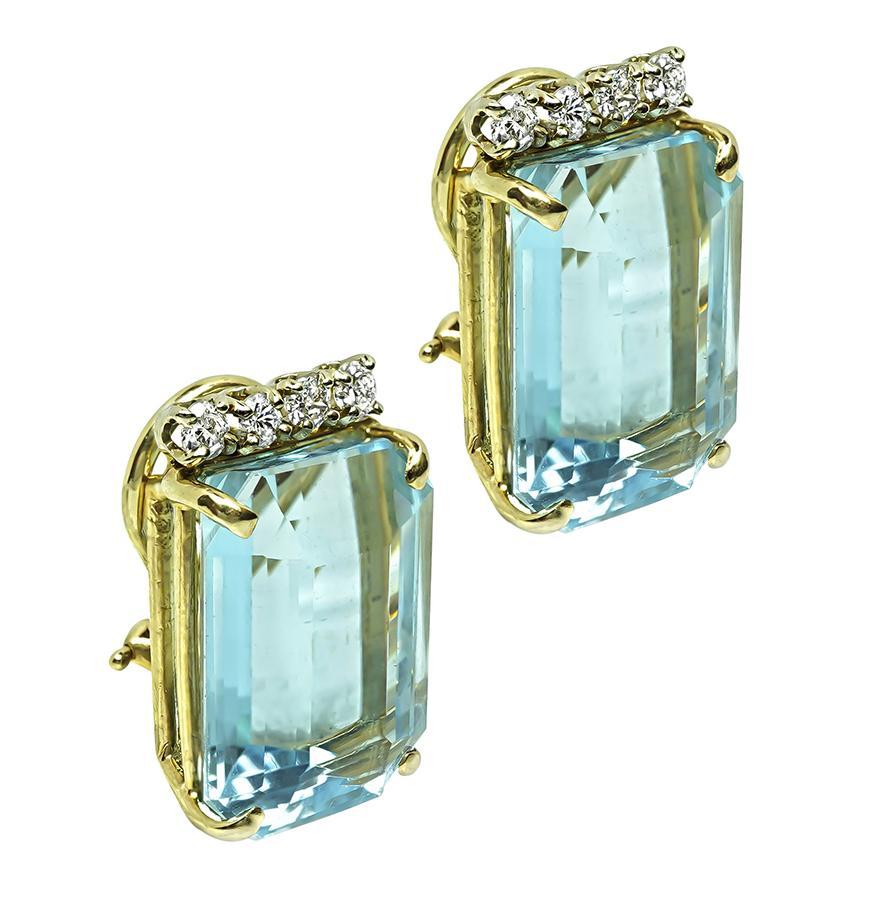 Voici une belle paire de boucles d'oreilles en or jaune 14k. Les boucles d'oreilles sont ornées d'aigues-marines de taille émeraude qui pèsent environ 50,00ct. Les aigues-marines sont mises en valeur par des diamants ronds étincelants pesant environ