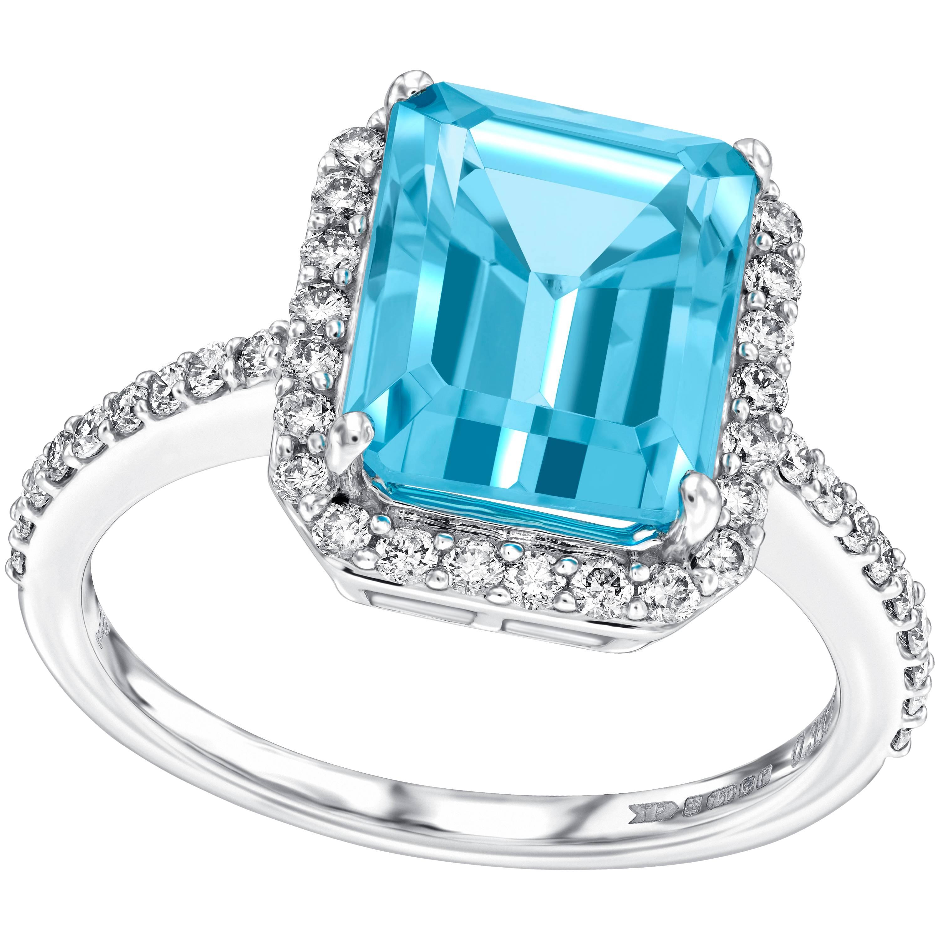 Cette magnifique bague de fiançailles en topaze bleue de 5,00 carats de taille émeraude est entourée d'un halo de diamants blancs ronds et brillants de 0,38 carat. Cette bague a un poids total de pierres précieuses de 5,38 carats. Avec une qualité