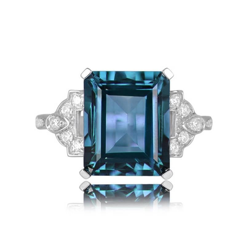 An exquisite 18k white gold ring showcasing a stunning emerald-cut blue topaz set securely in prongs. The center stone, boasting an impressive 5-carat approximate weight, takes center stage. The shoulders of the ring feature a captivating geometric