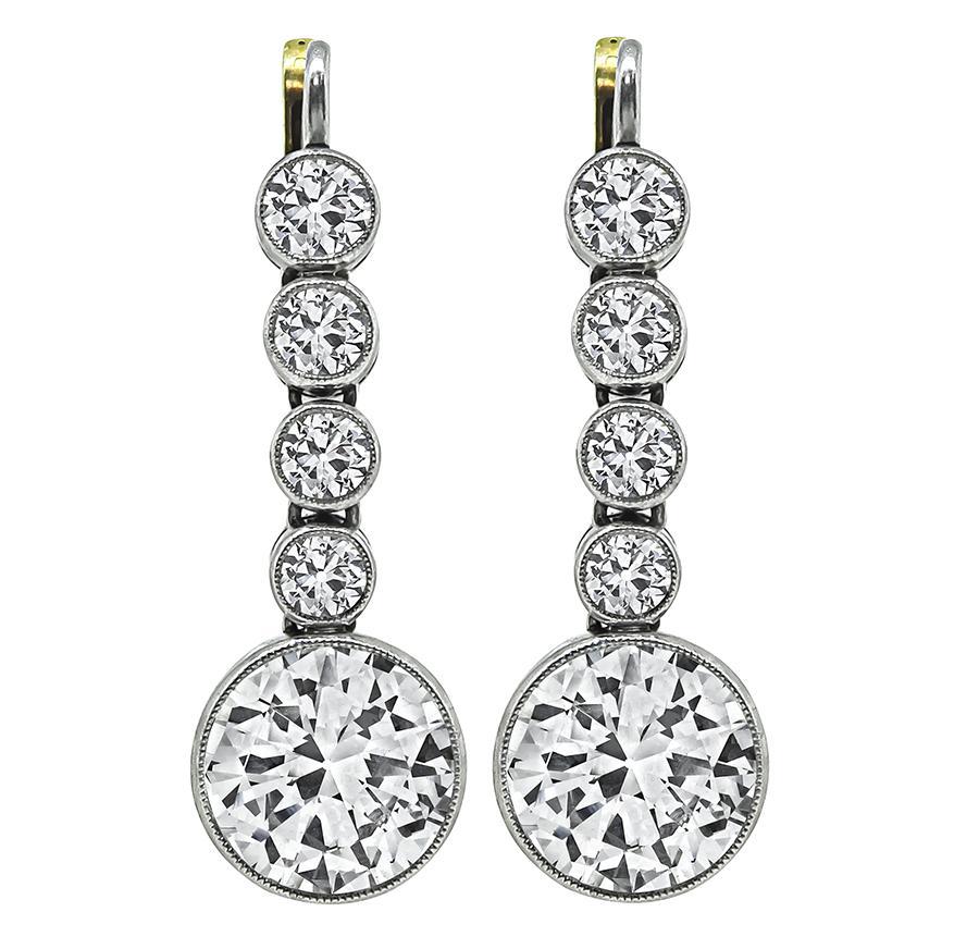 This is a stunning pair of platinum and gold earrings. The earrings feature two sparkling old European cut diamonds that weigh approximately 4.50ct. The color of the diamond is H with VS2 clarity. The diamonds are accentuated by dazzling small old