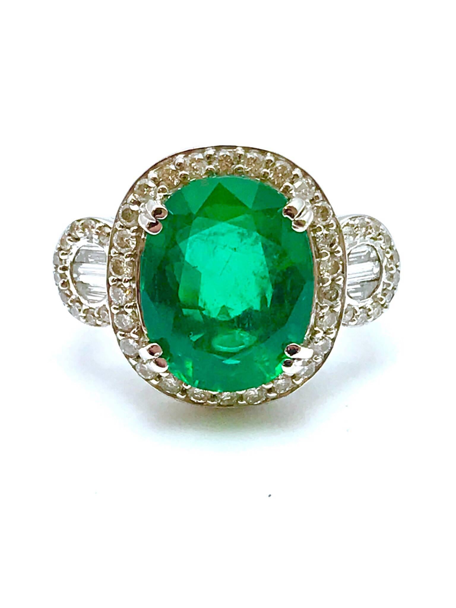 A 5.01 carat oval natural emerald and diamond 18 karat white gold cocktail ring.  The emerald is set with four double prongs, framed by a single row of round brilliant cut diamonds, leading into a diamond half shank.  There are 60 diamonds, with a