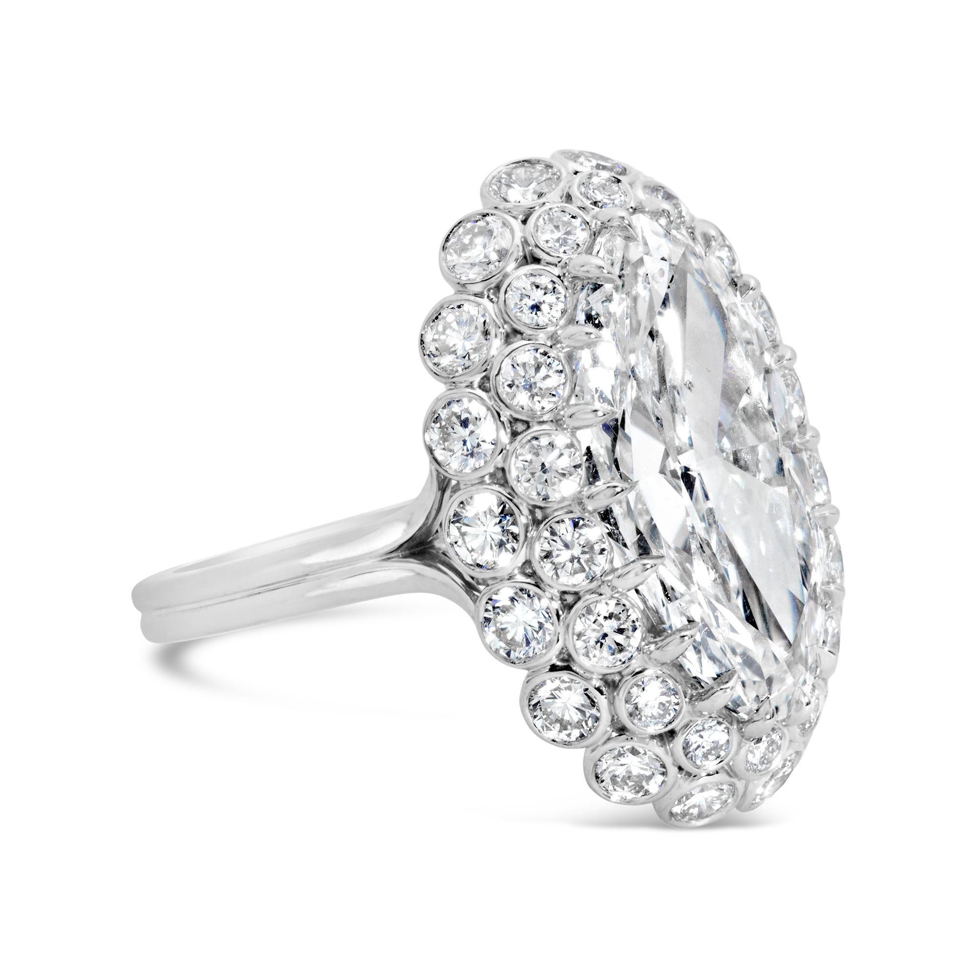 A stunning fashion ring, showcasing a 5.01 carats oval cut diamond with J color and SI2 clarity, set on an eighteen prong setting. Surrounded by a cluster of bezel-set round brilliant cut diamonds weighing 1.92 carats total. Finely made with a