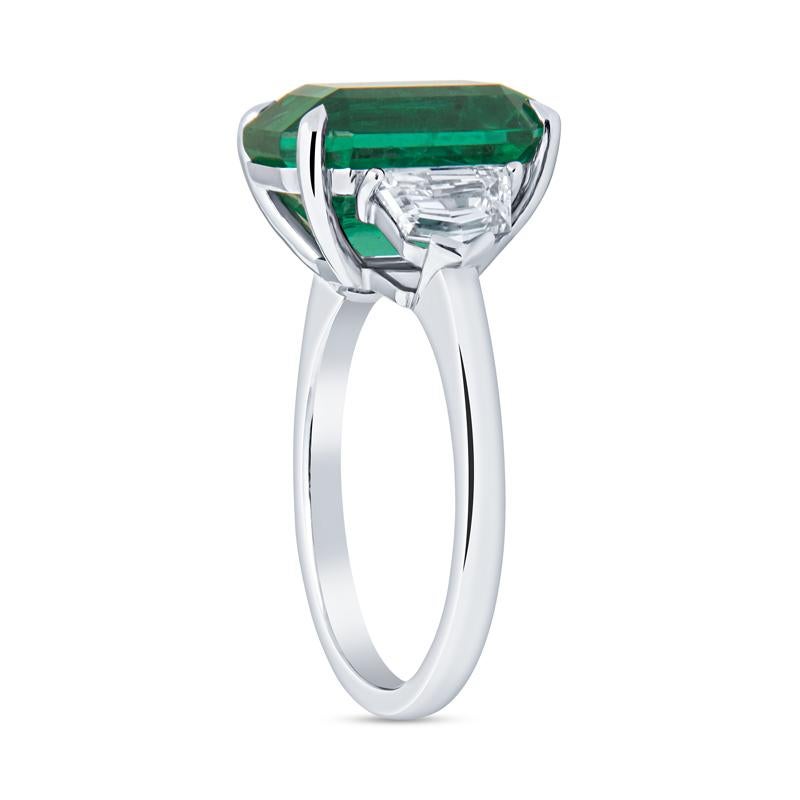 This beautiful ring features a 5.02 carat emerald cut natural emerald accented by 1.02 carat total weight in two cadillac cut diamonds set in platinum. The emerald has a high level of transparency and strong green saturation. This is a one of a kind