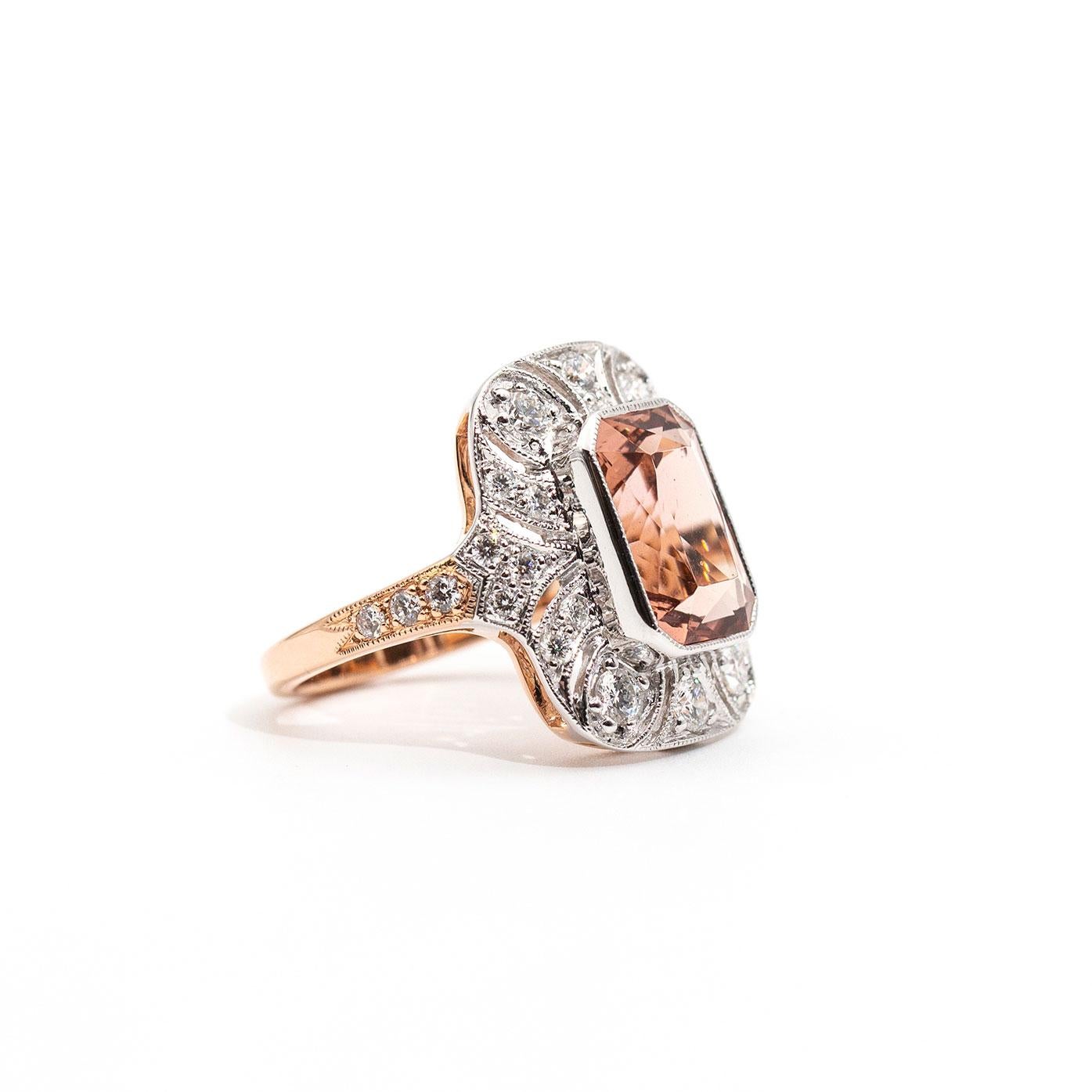 Forged in 18 carat rose and white gold, this captivating vintage-inspired ring features a gorgeous 5.02 carat bright salmon colour modified radiant cut natural morganite. This stunning centrepiece is surrounded by an intricately pierced border set