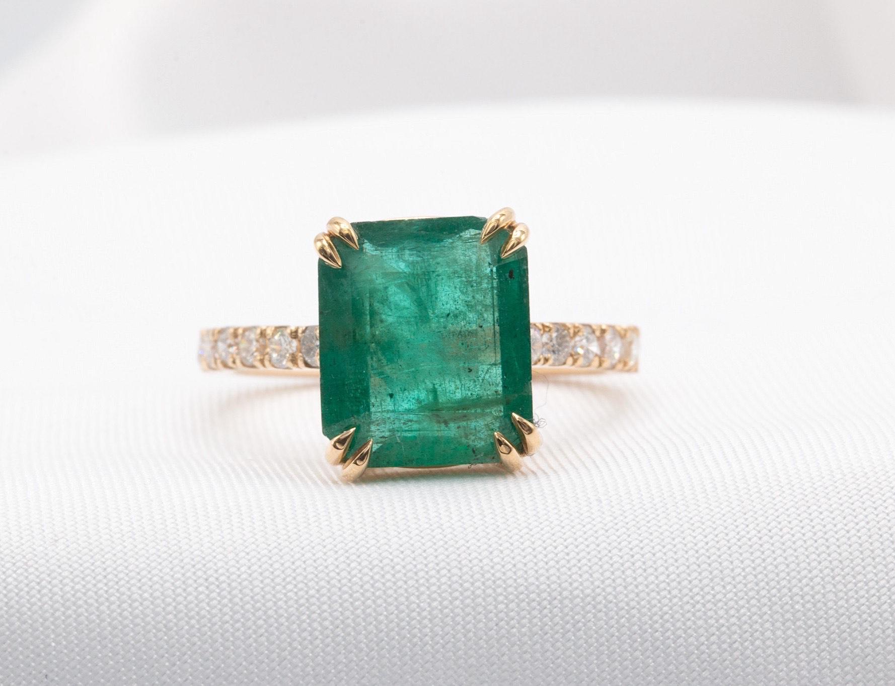 This Zambian emerald and diamond ring will be an excellent addition to your gemstone jewelry collection!
Use it as an engagement ring or as an anniversary birthstone surprise.
The ring features a beautiful lush green Zambian emerald weighing 5.02