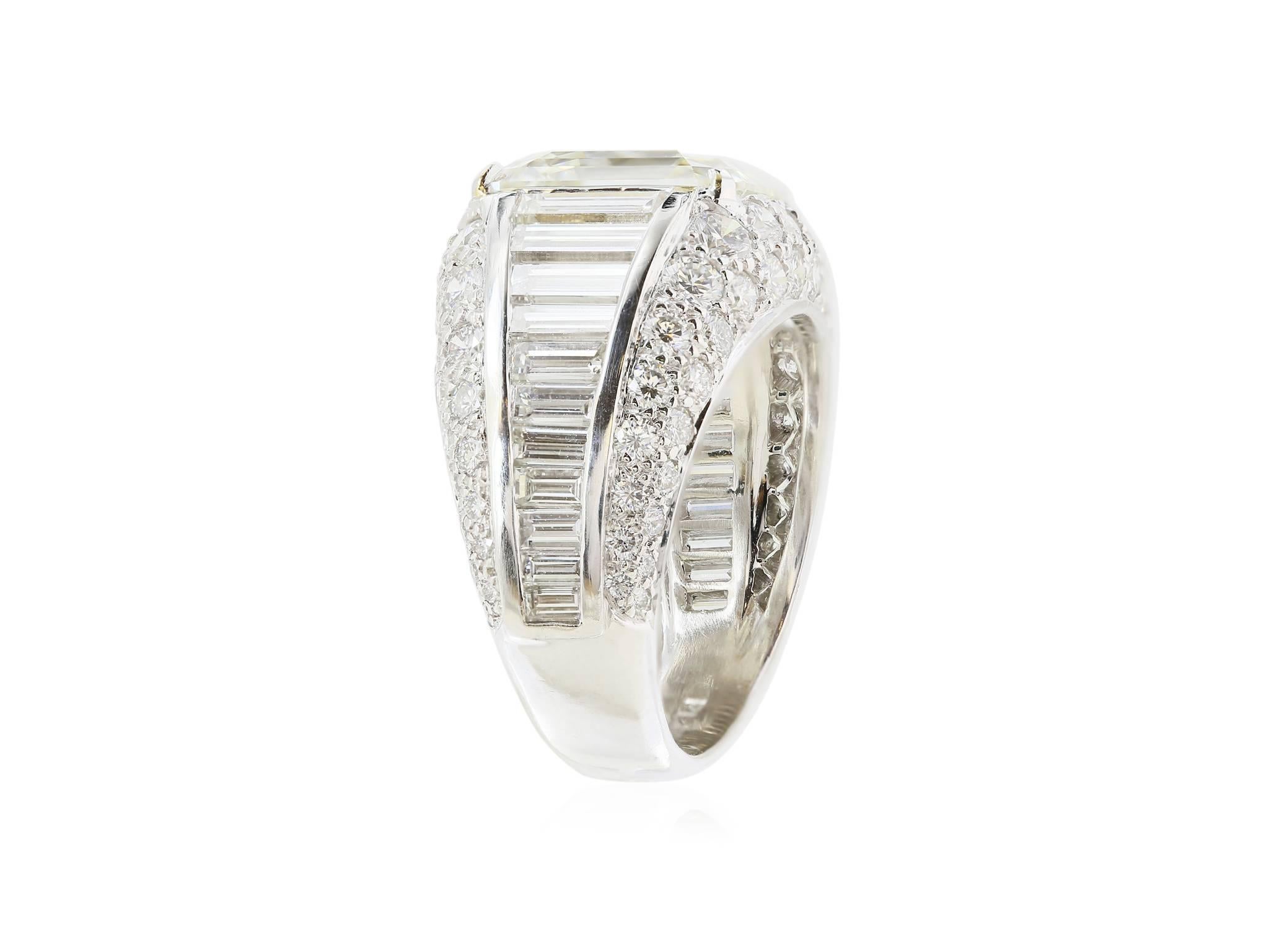 Platinum cluster diamond ring featuring one 5.02ct Emerald cut diamond of near colorless and very clean clarity, The diamond mounting consists of 11 graduating diamond baguettes on both sides of the shoulders with pave set diamonds on both sides of