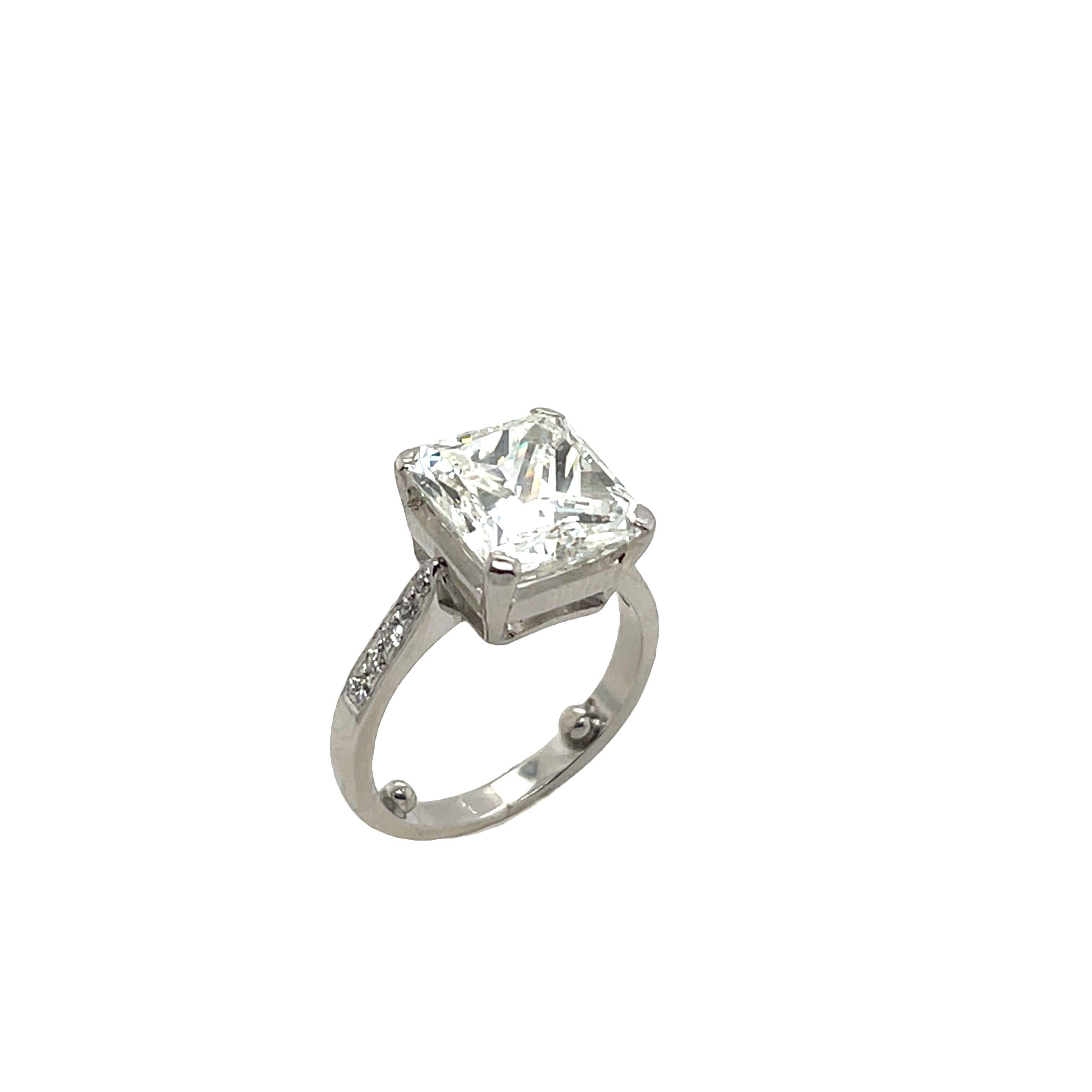Un exquis diamant naturel de 5,02ct de taille radieuse, 
de couleur I et de pureté SI1, est la pièce maîtresse de la collection. 
de cette luxueuse bague en platine avec de petits diamants sur les épaules. La taille rayonnante rehausse l'éclat et le