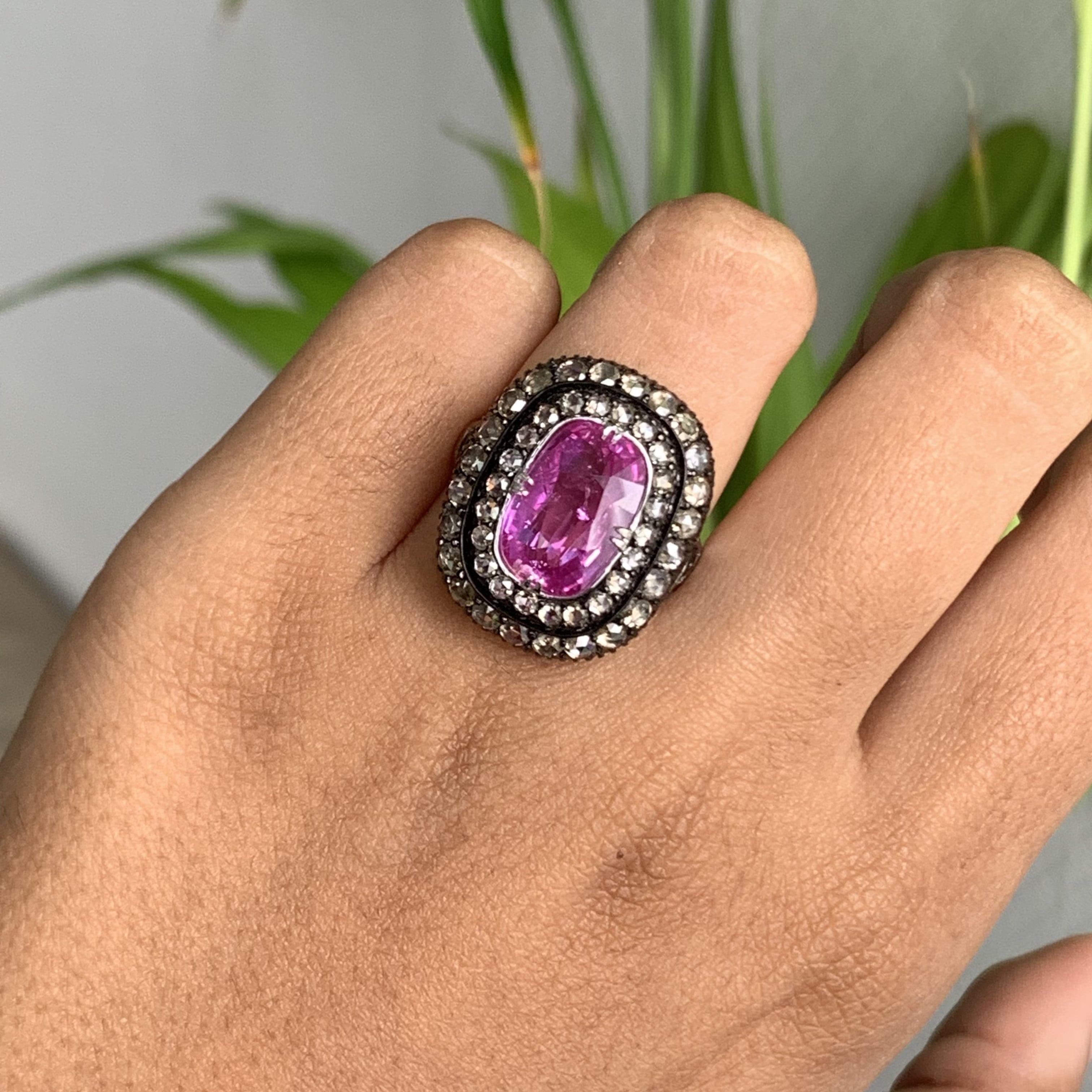 Presenting a remarkable statement ring meticulously handcrafted to evoke a captivating antique aesthetic. This extraordinary piece showcases a 5.03 carat Pink Sapphire, originating from Madagascar, which has only undergone normal heat treatment,