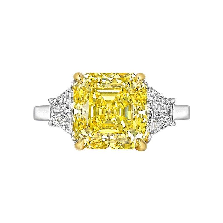 Diamond ring, centering a natural fancy vivid yellow square emerald-cut diamond weighing 5.03 carats flanked by colorless trapezoid-cut diamonds, mounted in platinum with 18k yellow gold.

Two trapezoid-cut diamonds weighing 1.05 total
