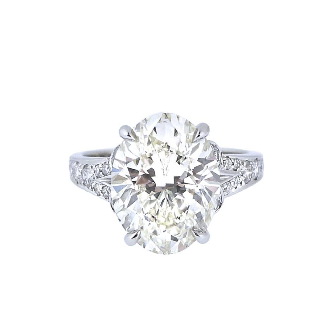 Large and beautifully cut oval diamond with GIA certificate number 1196270888 stating the diamond is L color and VS1 clarity with faint fluorescence.  The mounting is platinum and set with 22 round brilliant cut diamonds that total .52 carats with a