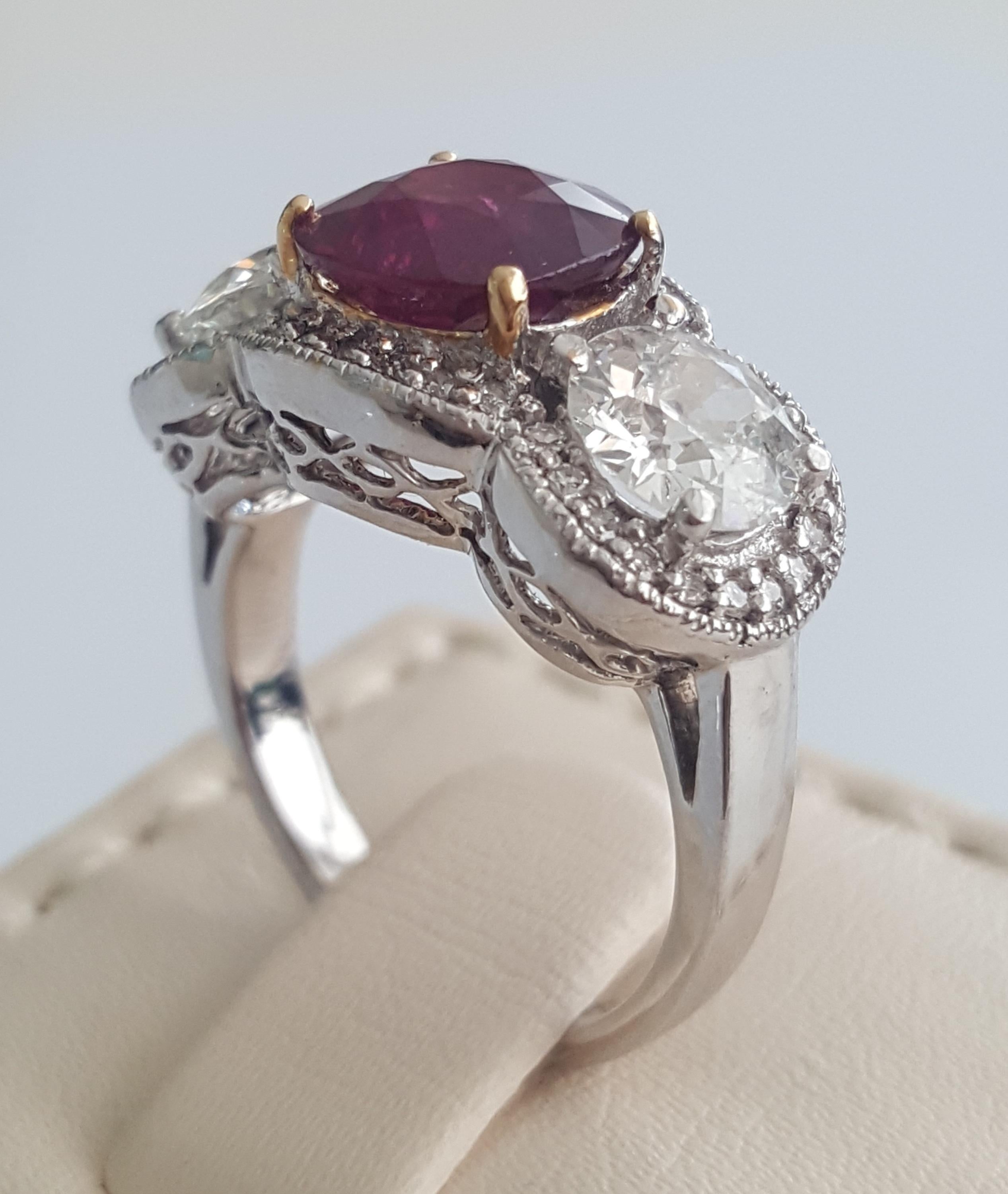 This understated, elegant and enticing three stone ring designed and manufactured by Moguldiam Inc features natural cushion ruby weighing 3.05 carat flanked by two round white old cut diamond weighing weighing 1.74 carat with H color and VS clarity