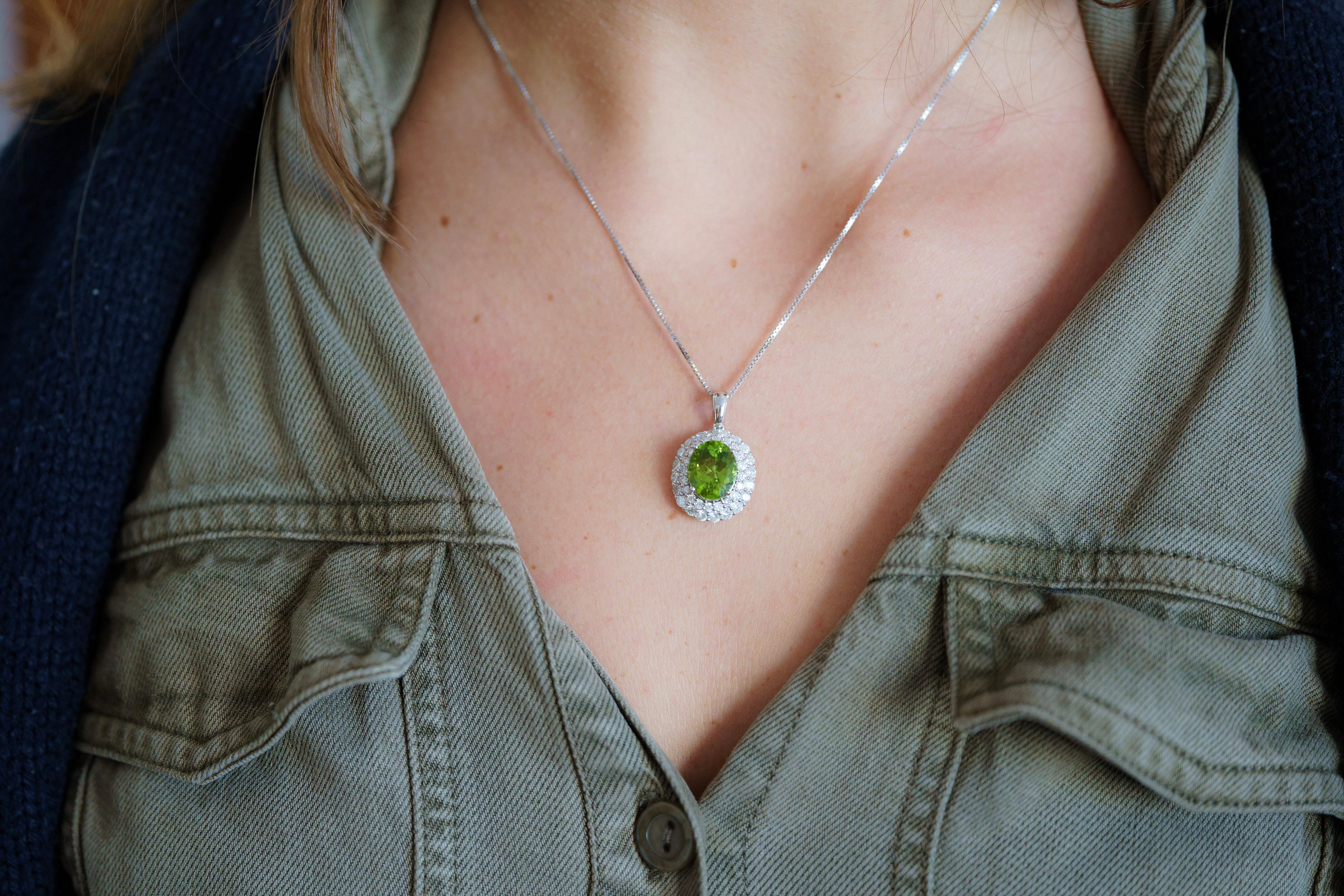 Presenting this extravagant Natural Green Peridot and Diamond Pendant, placed neatly in 18K White Gold.

This pendant features a vibrant oval-cut natural 5.03 carat peridot center in a prong setting, radiating a green hue. Paired with 1.74 carats