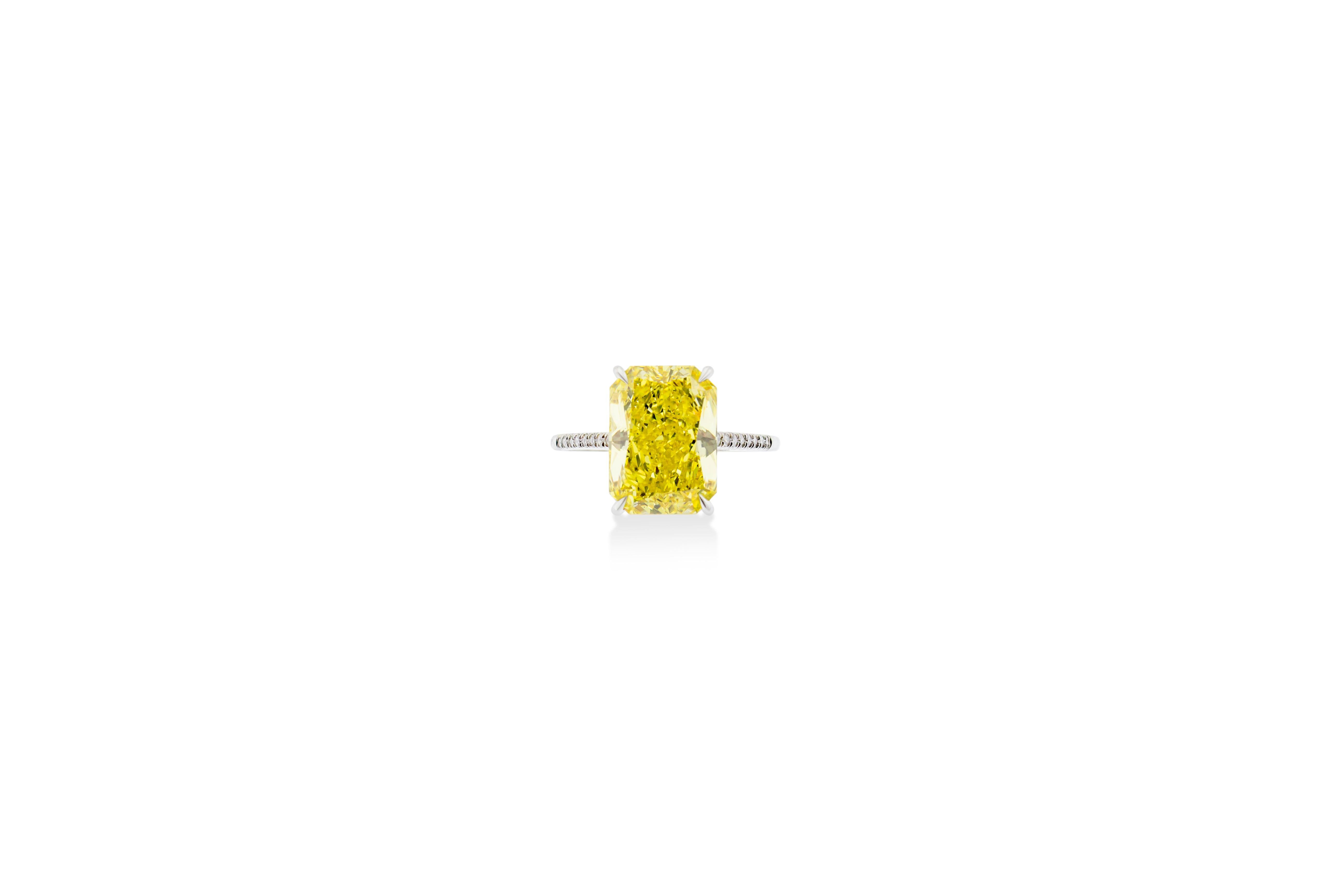 Fancy vivid yellow 5.04 carat rectangular radiant cut diamond engagement ring. Mounted in 2.7g of Platinum with a delicate thin  half diamond pave encrusted band. GIA Certified. Certificate No. 6183449015. Size 6.5.

Resizing available upon request.