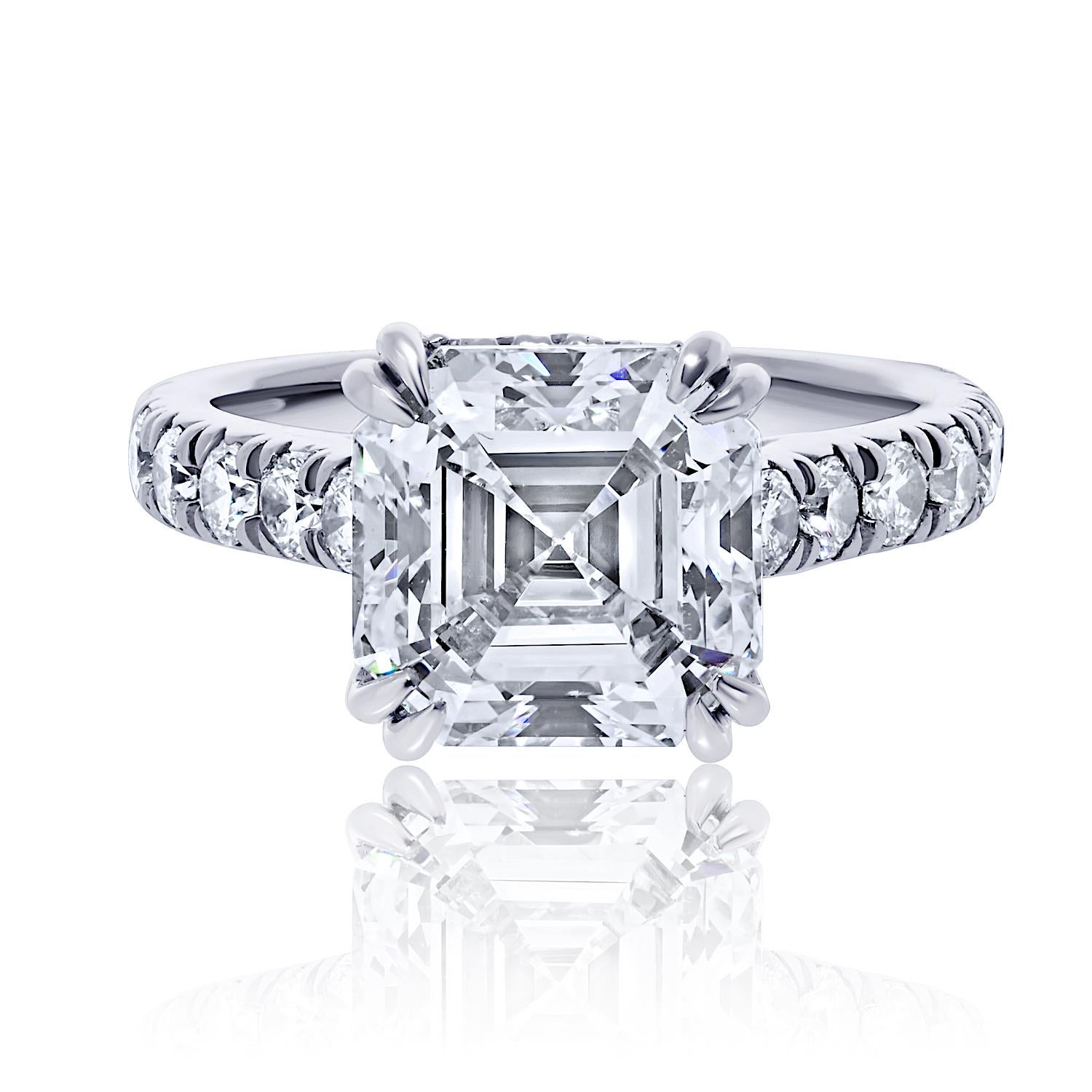 This striking engagement ring features a mesmerizing 5.01 carat Asscher cut center diamond, certified by GIA as H color and SI1 clarity. With its dramatic step-cut facets and bold, geometric shape, the Asscher cut exudes timeless Art Deco
