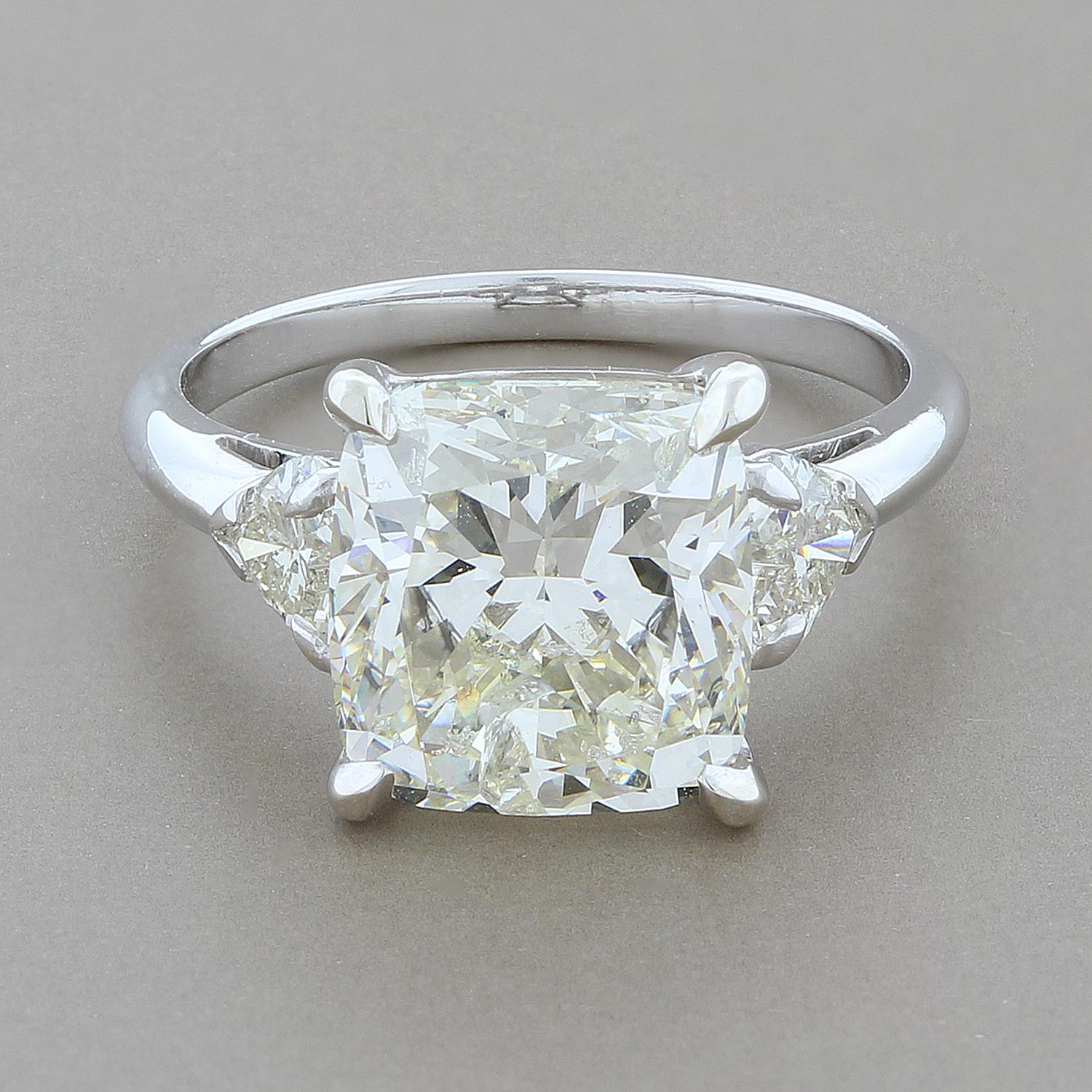 A beautifully cut 5.05 carat cushion cut diamond with brilliance and fire that will match any other diamond on the market. Two heart shape diamonds are mounted on the sides of the cushion cut, set in 18K white gold. 
A bargain of a price, all the