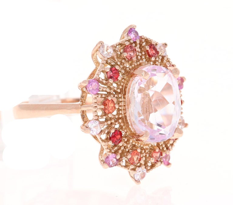 This beautiful vintage inspired setting with a modern colorful theme has an Oval Cut Kunzite weighing 4.13 carats and is surrounded by 20 Round Cut Multi-Colored Sapphires that weigh 0.92 Carats. The total carat weight of the ring is 5.05 Carats.