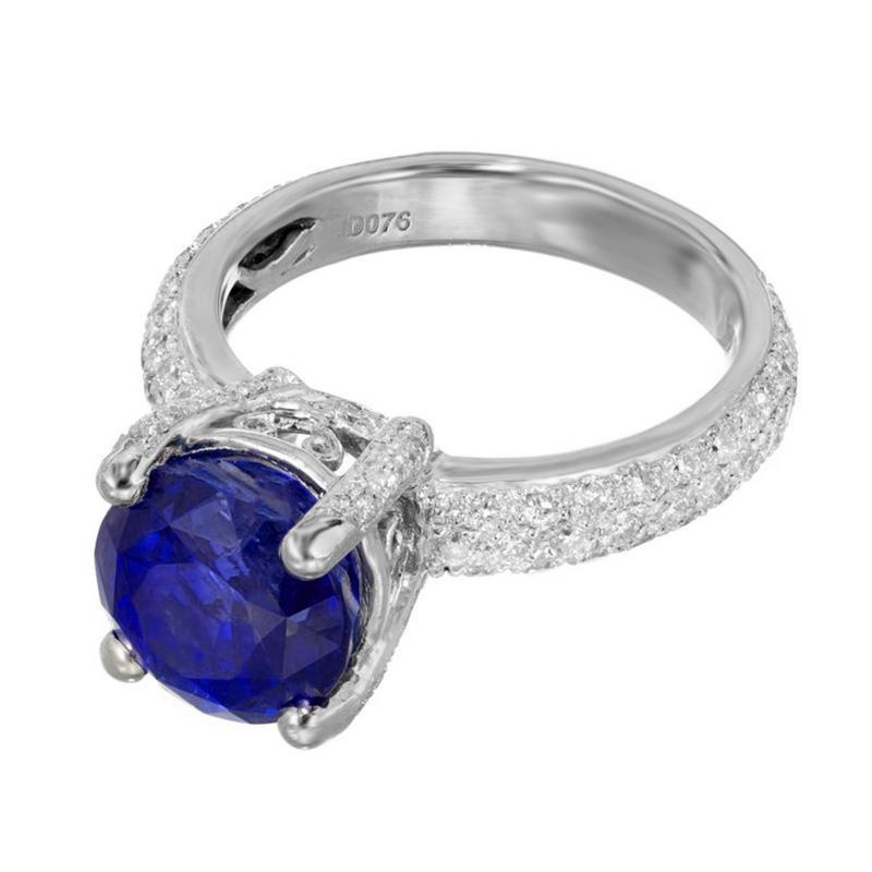 Round sapphire and diamond handmade engagement ring. Rich blue with a hint of purple round sapphire center stone, mounted in a platinum setting, beautifully accented with 122 round diamonds along 3 squares of the shank and crown.  AGL certified
