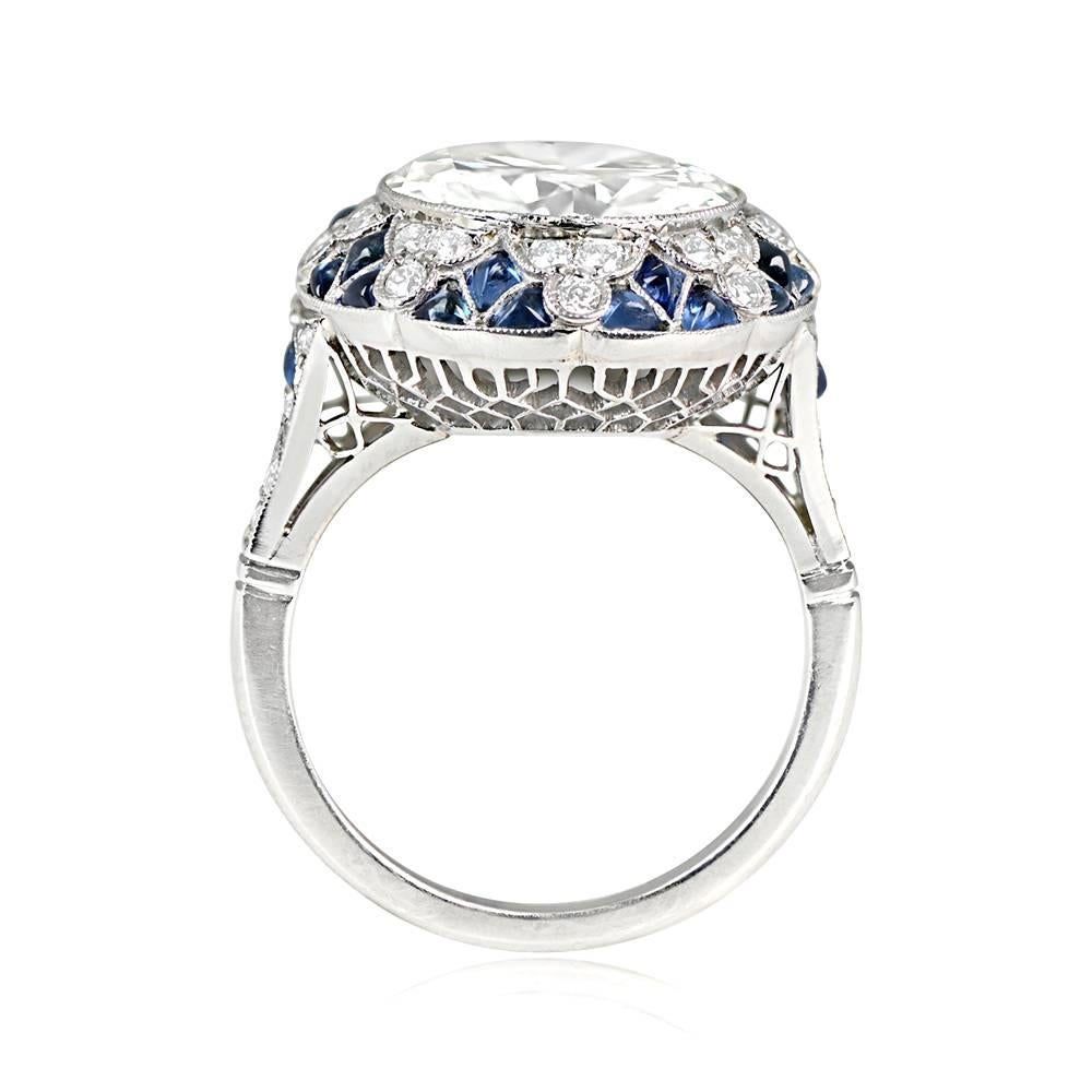 This is a stunning art deco-inspired ring showcases a stunning 5.05 carat transitional cut diamond, bezel-set and encircled by a mesmerizing geometric halo composed of old European cut diamonds and cabochon cut sapphires arranged in a starburst