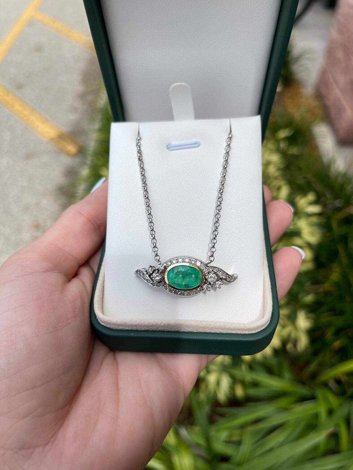 A vintage, 5.05 carat Colombian emerald and diamond bib gold necklace. Handcrafted in solid 14k white & yellow gold, the vintage piece showcases an oval shape Colombian emerald that is nestled in a yellow gold bezel setting. A vintage, diamond halo