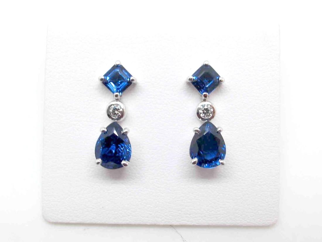 These regal, royal blue sapphire and diamond earrings are elegant and timeless. Two pear shape royal blue sapphires are suspended from a pair of princess cut blue sapphires. Two small diamonds accent the sapphires and add sparkle. This pair of