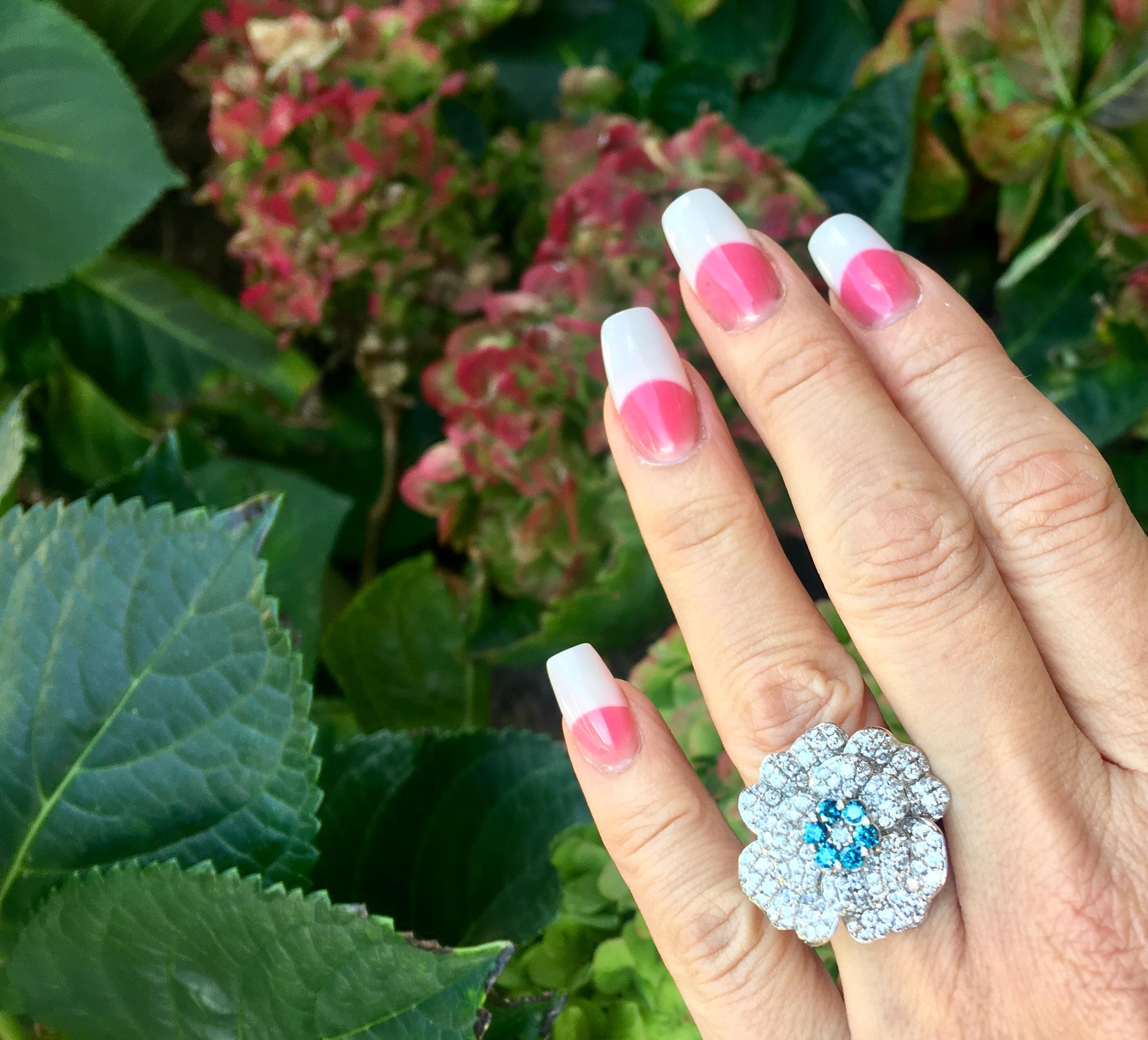 Magnificently styled and stunning in real life, 18 karat white gold estate cocktail ring in the shape of a 3 dimensional camellia flower features approximately 213 round brilliant, prong set white diamonds and 6 blue diamonds.

213 white diamonds in