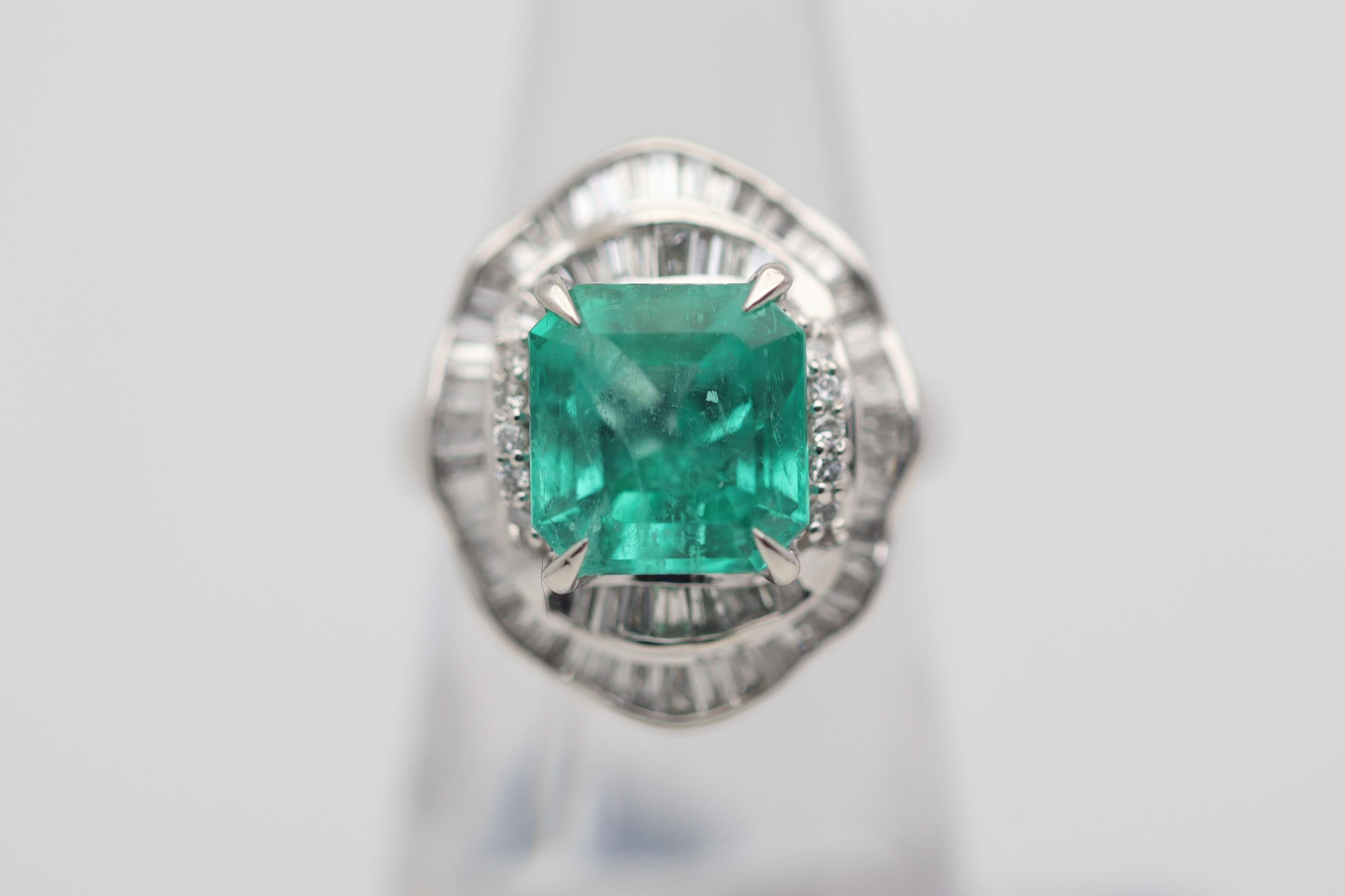 A fine platinum ring featuring a 5.08 carat emerald. It has a bright brilliant green color and most likely originates from Colombia. It is accented by 1.21 carats of round brilliant and baguette-cut diamonds set around the emerald in a stylish