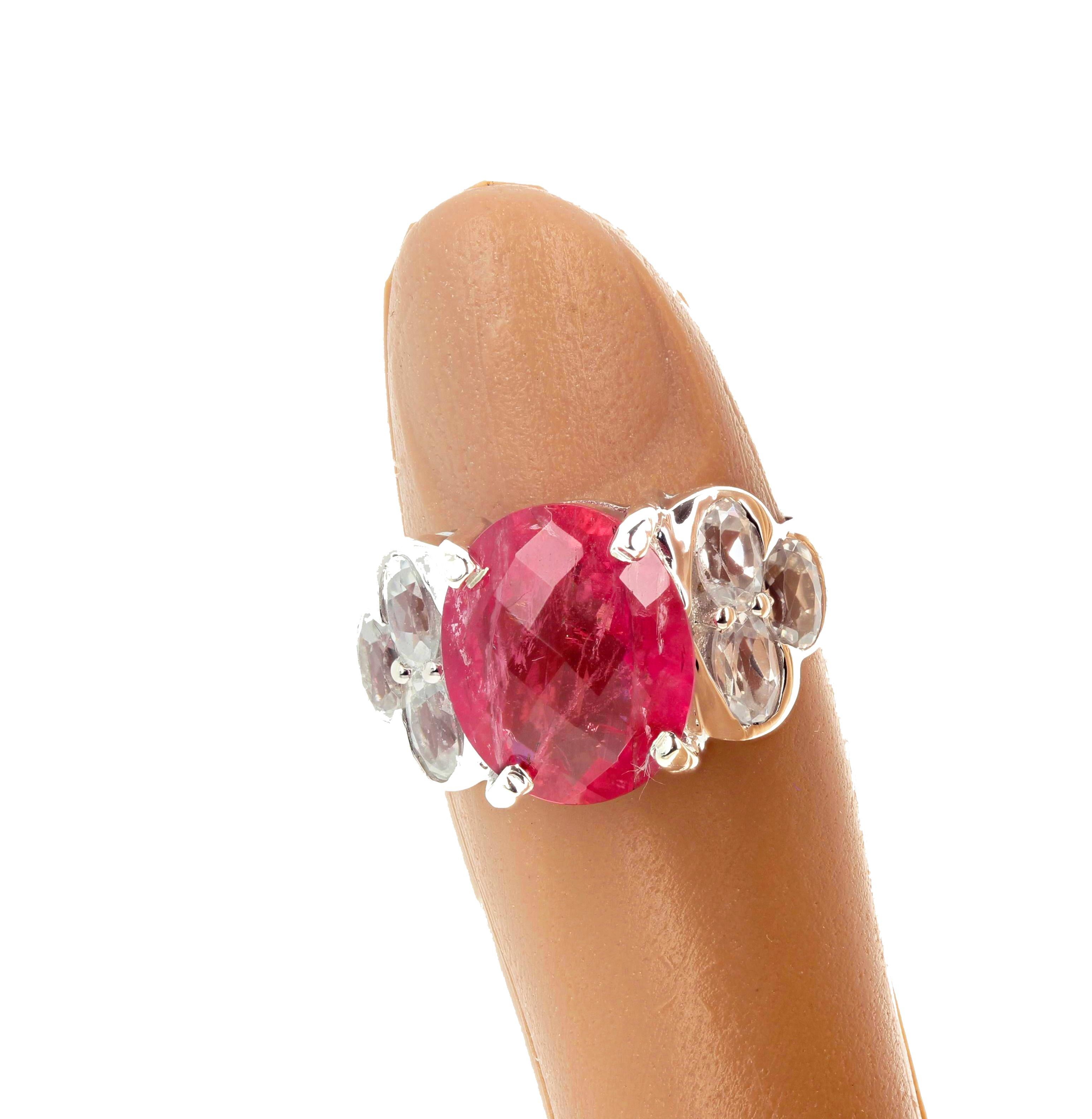 Glittering checkerboard gem cut 13.2 mm x 10.8 mm natural Pink Tourmaline set in a rhodium plated sterling silver ring accented with sparkling white natural Topaz gemstones.  This Tourmaline ring is a size 7 (sizable for free). Spectacular optical