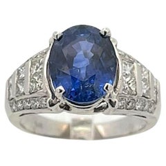 Anillo de zafiro oval de 5,08ct con diamantes redondos brillantes y talla princesa de 1,00ctw
