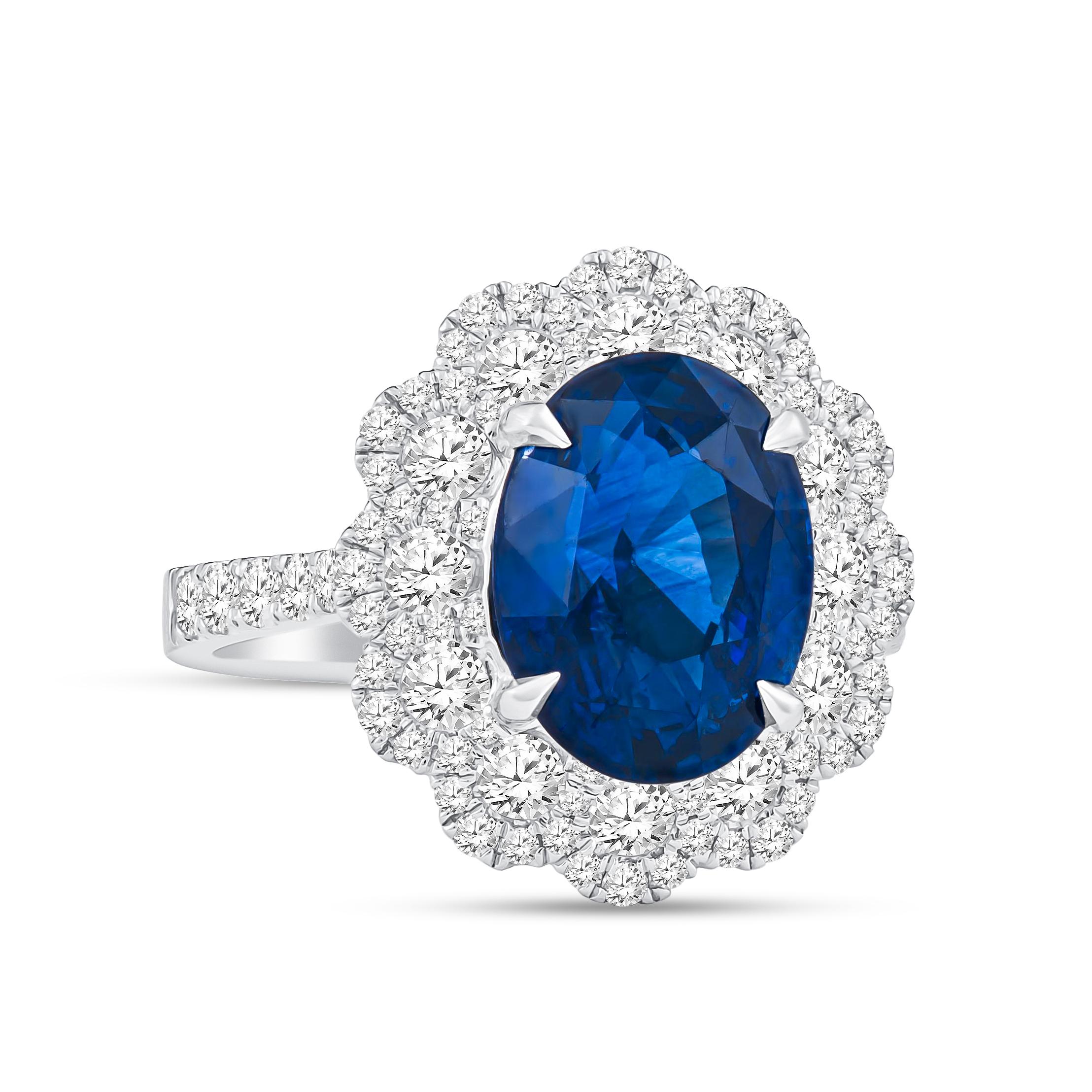 Gorgeous 18k white gold flower style ring spotlighting a GIA graded natural vivid blue 5.09 carat oval sapphire that is surrounded by 1.14 carats total of fine round brilliant cut diamonds. Crafted in a size 6.5 and may be resized to larger or