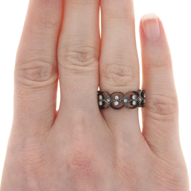 Elegant sophistication awaits with this stunning ring! Showcasing a black rhodium finish, this 18k white gold eternity band features an ornate open cut motif highlighted by sparkling diamonds and sweet milgrain work.   

This ring is a size 5