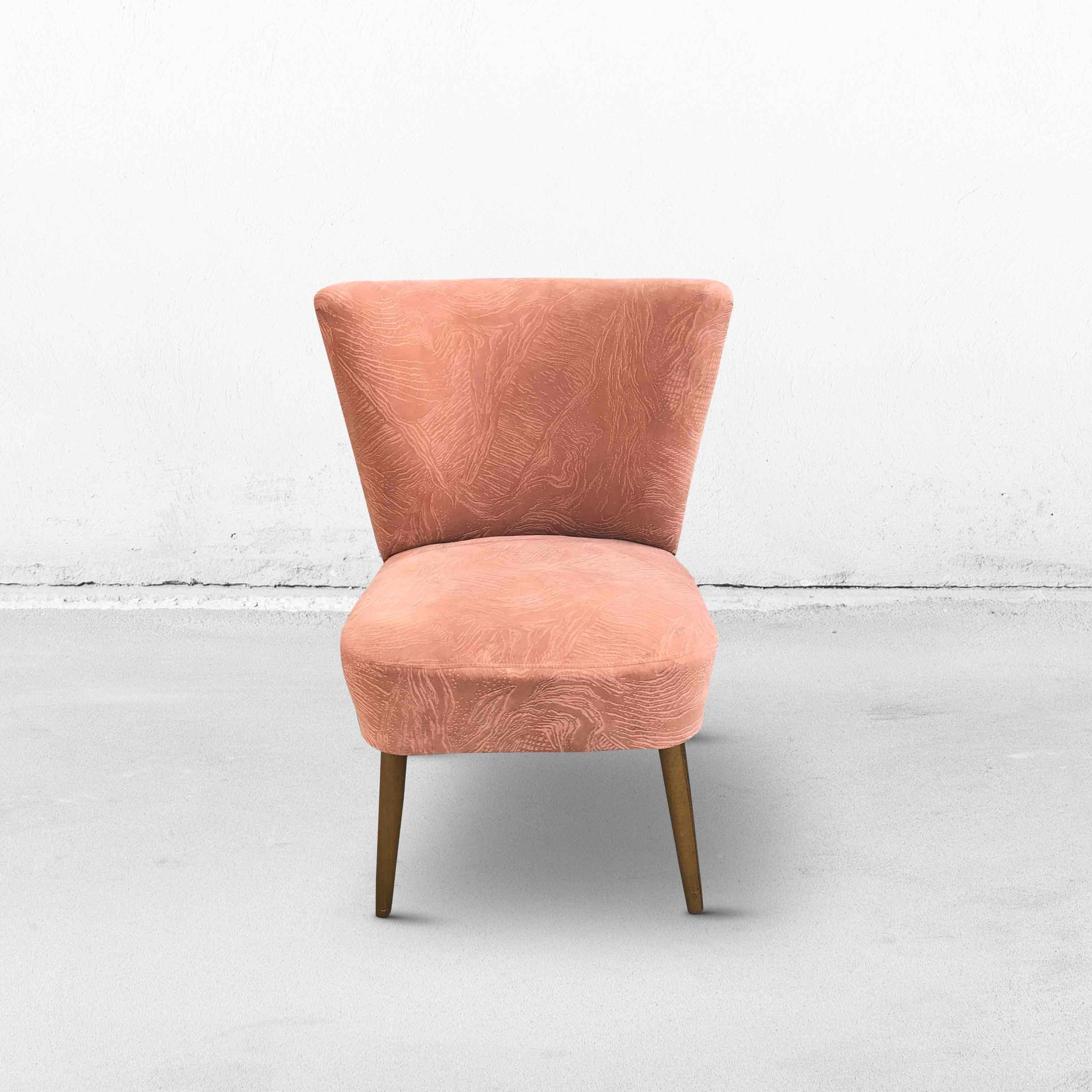 Cocktail chair in salmon pink with flared wooden legs. This model is sometimes referred to as an 'Expo '58' seat, since these chairs were used during the World Exhibit of 1958 in Brussels, Belgium. 
The seating comfort is still very good! The legs