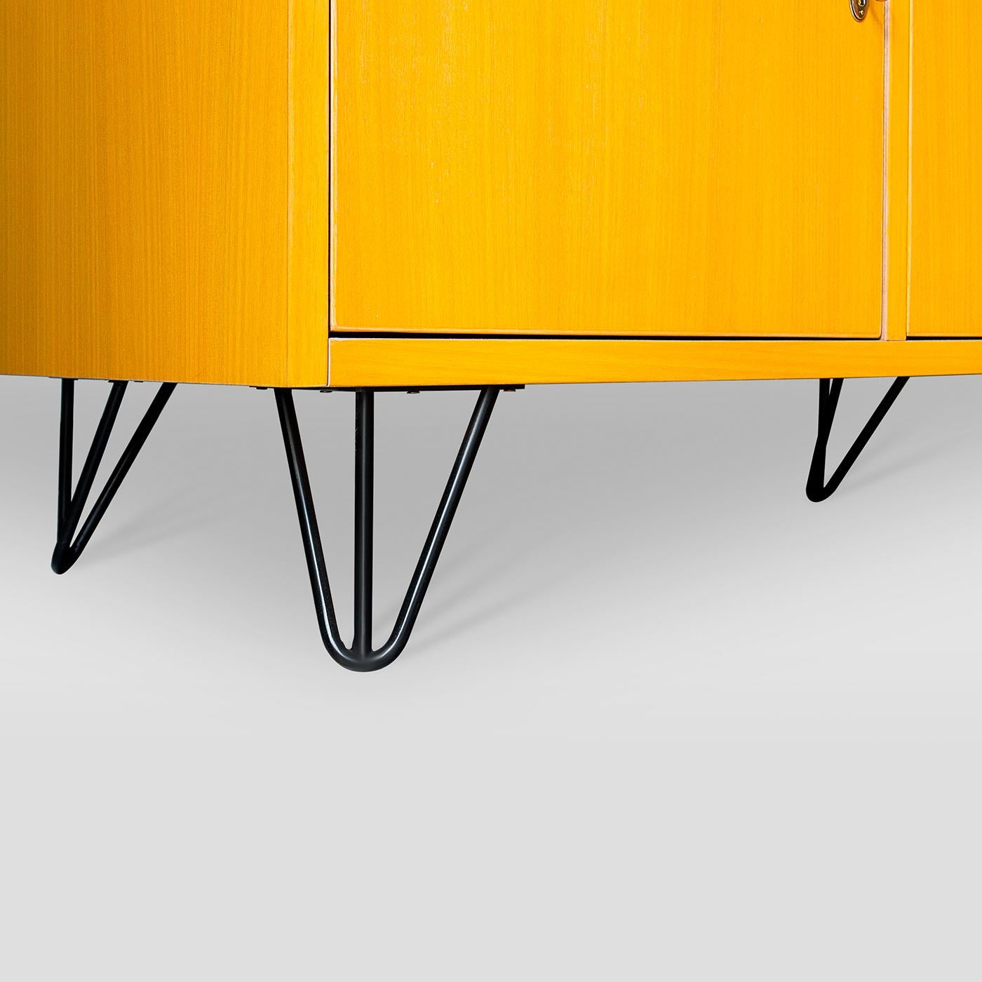 L'utilisation de chêne massif, mis en valeur par sa finition naturelle à l'intérieur et teinté en jaune vif à l'extérieur, définit ce meuble élégant et emblématique des années 50. Montée sur des pieds en fil métallique, elle offre trois vastes