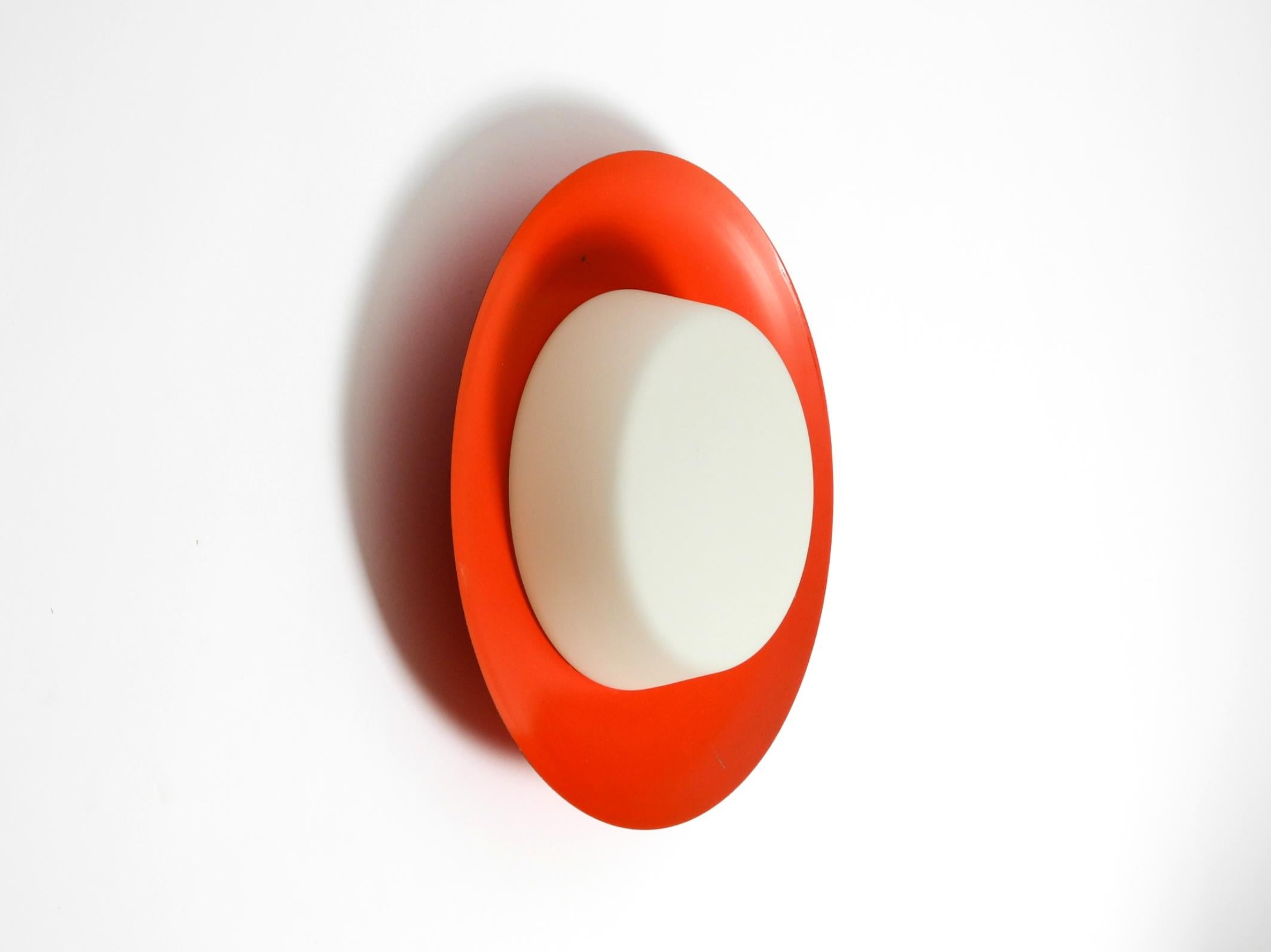 Große Mid Century Wand- oder Deckenleuchte aus Glas mit einem Metallreflektor in Rot.
Großartiges minimalistisches Design im Stil der 1950er Jahre. Hersteller ist Kaiser Leuchten. Hergestellt in Deutschland.
Voll funktionsfähig und 100% original.