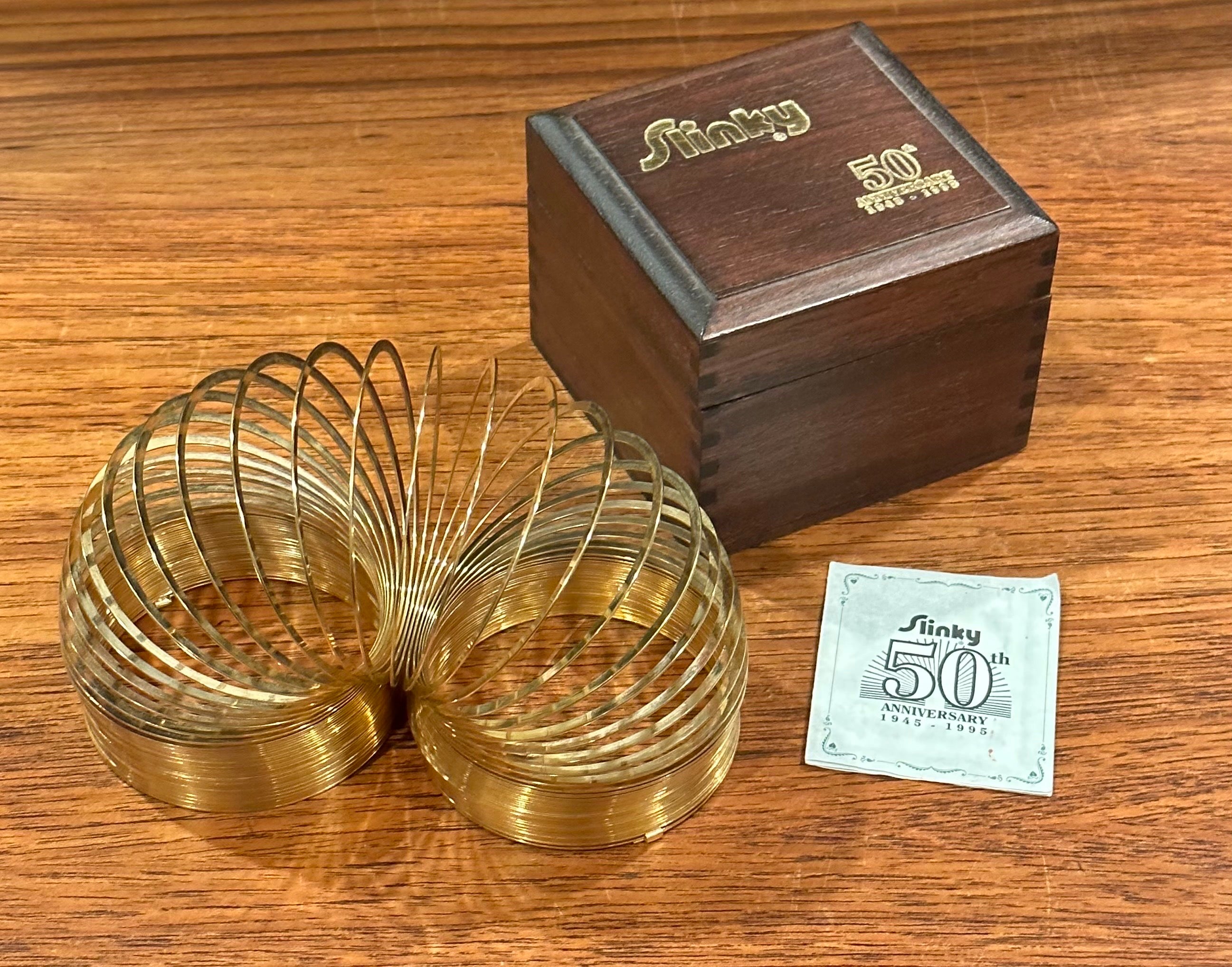 50th Anniversary gold-plated brass Slinky toy in wood box, circa 1995. This item is in very good vintage condition and appears to never have been played with. This Slinky was released in 1995 to celebrate the toy's 50th anniversary; this is a very