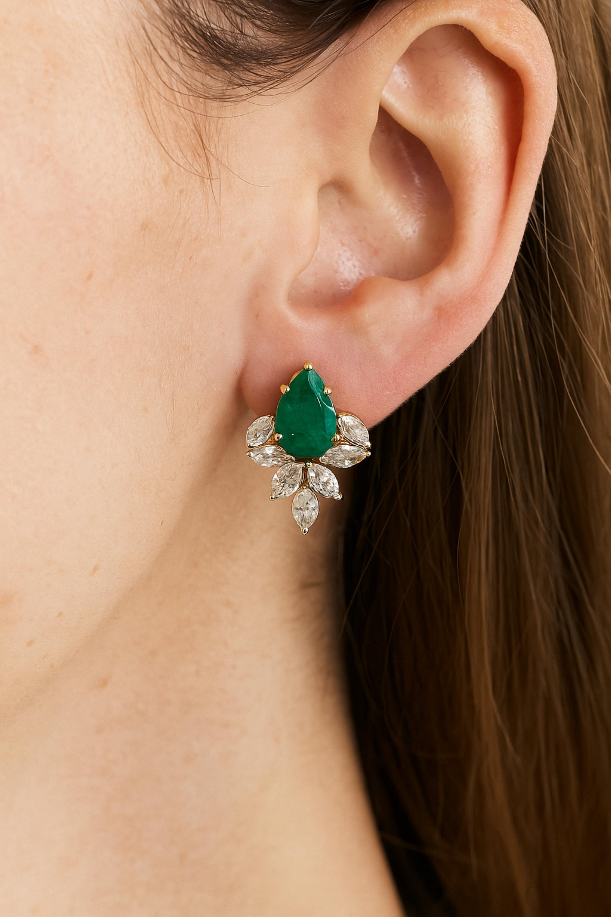 Ces boucles d'oreilles en or jaune 18 carats de 5,1 carats sont ornées d'une superbe émeraude en forme de poire, encadrée par un halo de diamants taillés en marquise, disposés comme un motif floral fleuri.
Les émeraudes sont des symboles d'amour, de
