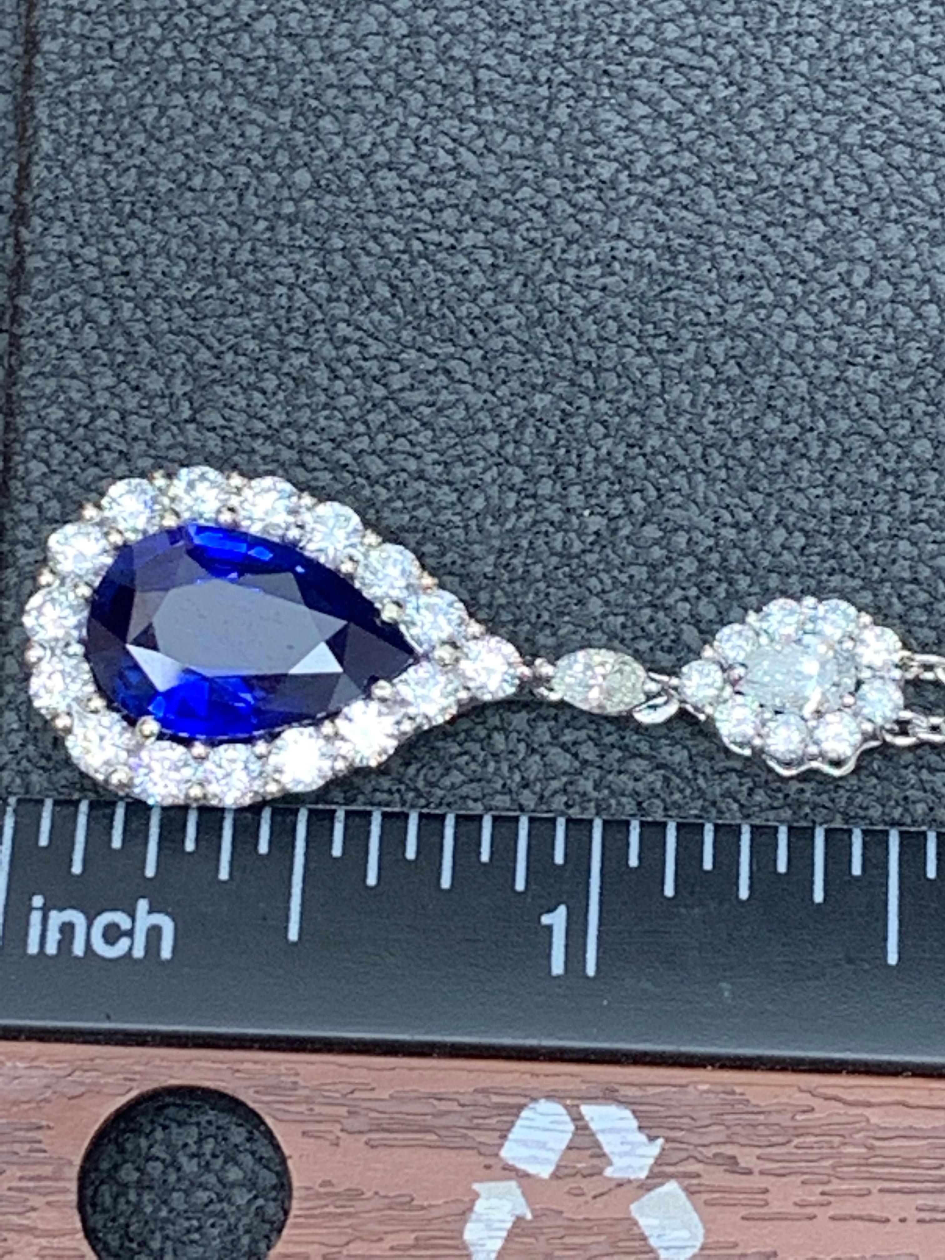 Showcasing a pear shape blue sapphire weighing 5.10 carats. Surrounded by a row of brilliant round diamonds. Pendant suspended on a pear shape diamond halo, attached to a diamond by the yard chain made in 18 karats white gold. Pear and Marquise