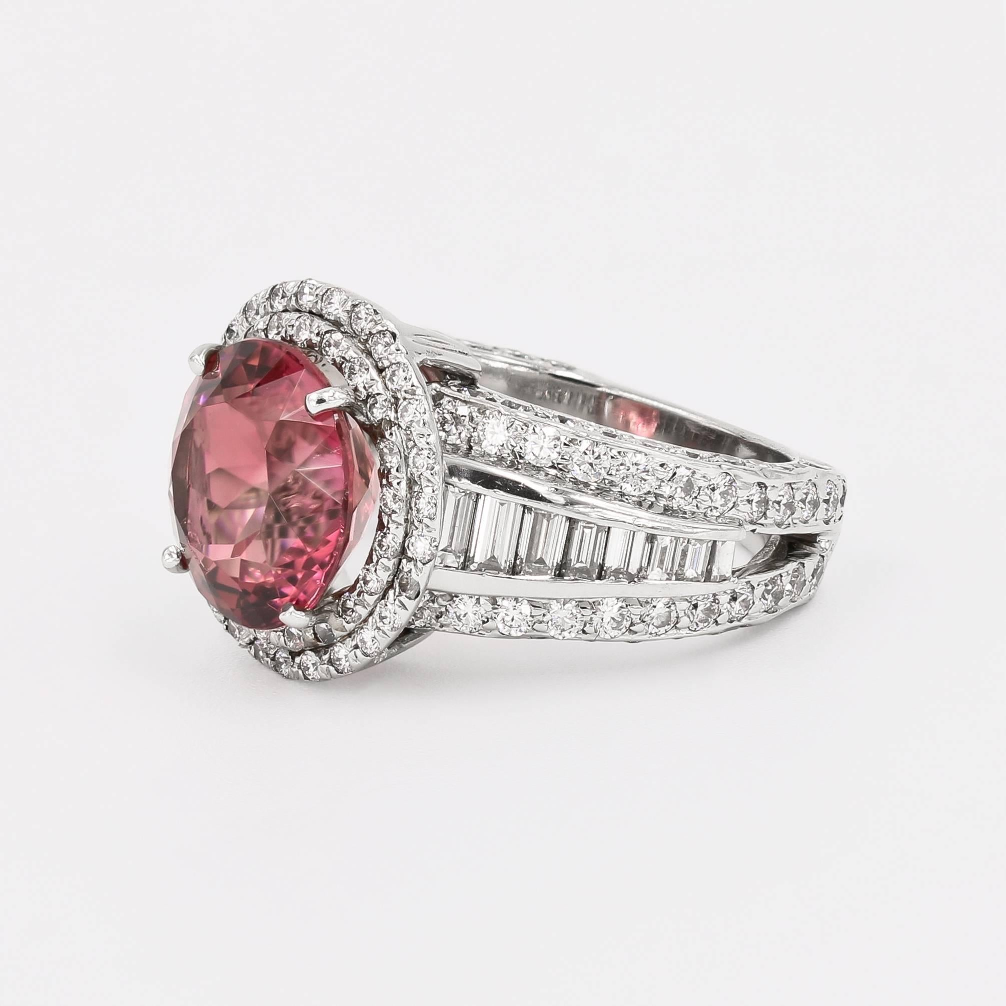 This impressive platinum ring contains a 5.10cts. round natural pink tourmaline center set in a double halo style setting. An abundance of diamonds accompany the center- 141 ideal cut round diamonds= 1.60cts. t.w. and 16 baguettes = .85ct. t.w.