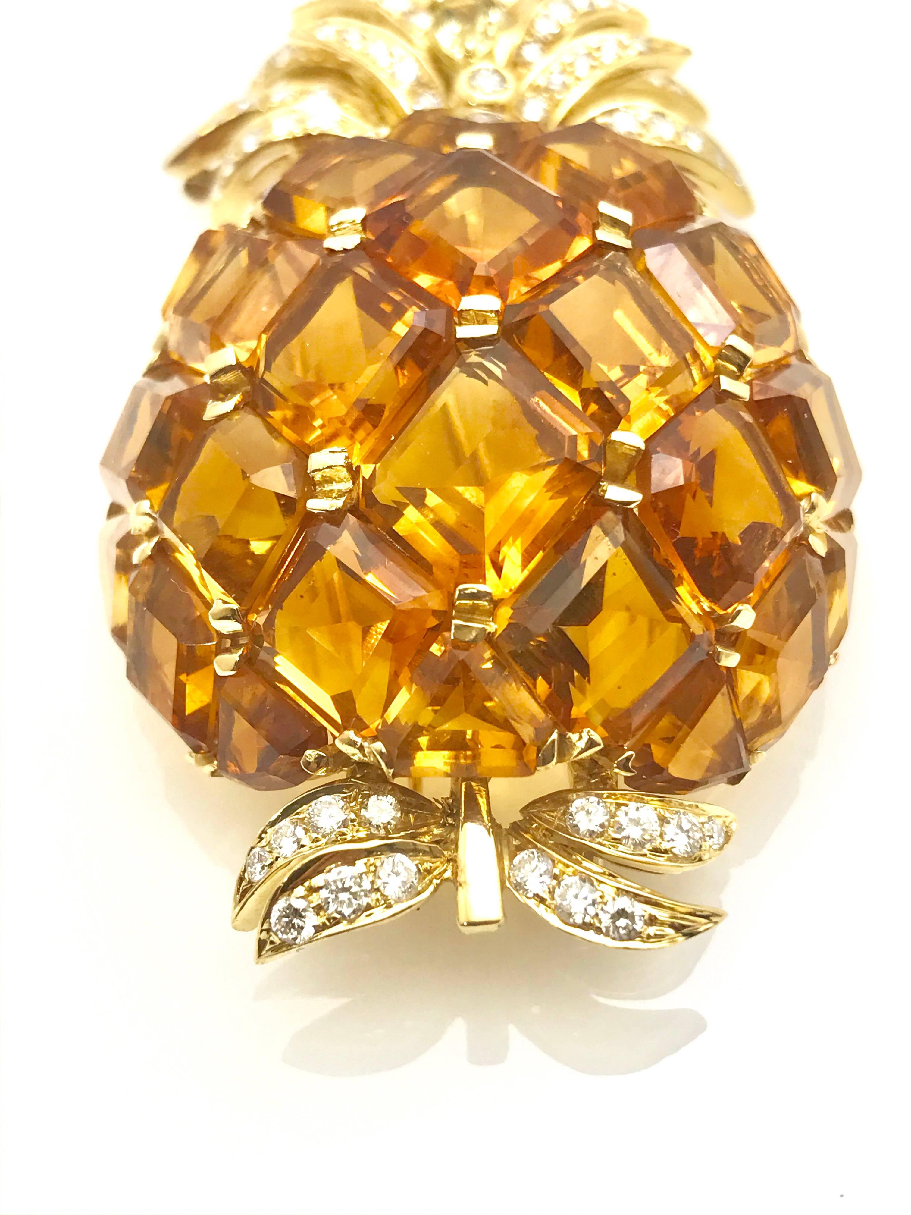 A 51.00 carat total weight citrine and diamond 18 karat yellow gold pineapple pendant brooch.  The square cut citrines are shared prong set, forming a dome oval shape together.  There is a total of 68 round brilliant diamonds forming the stem and