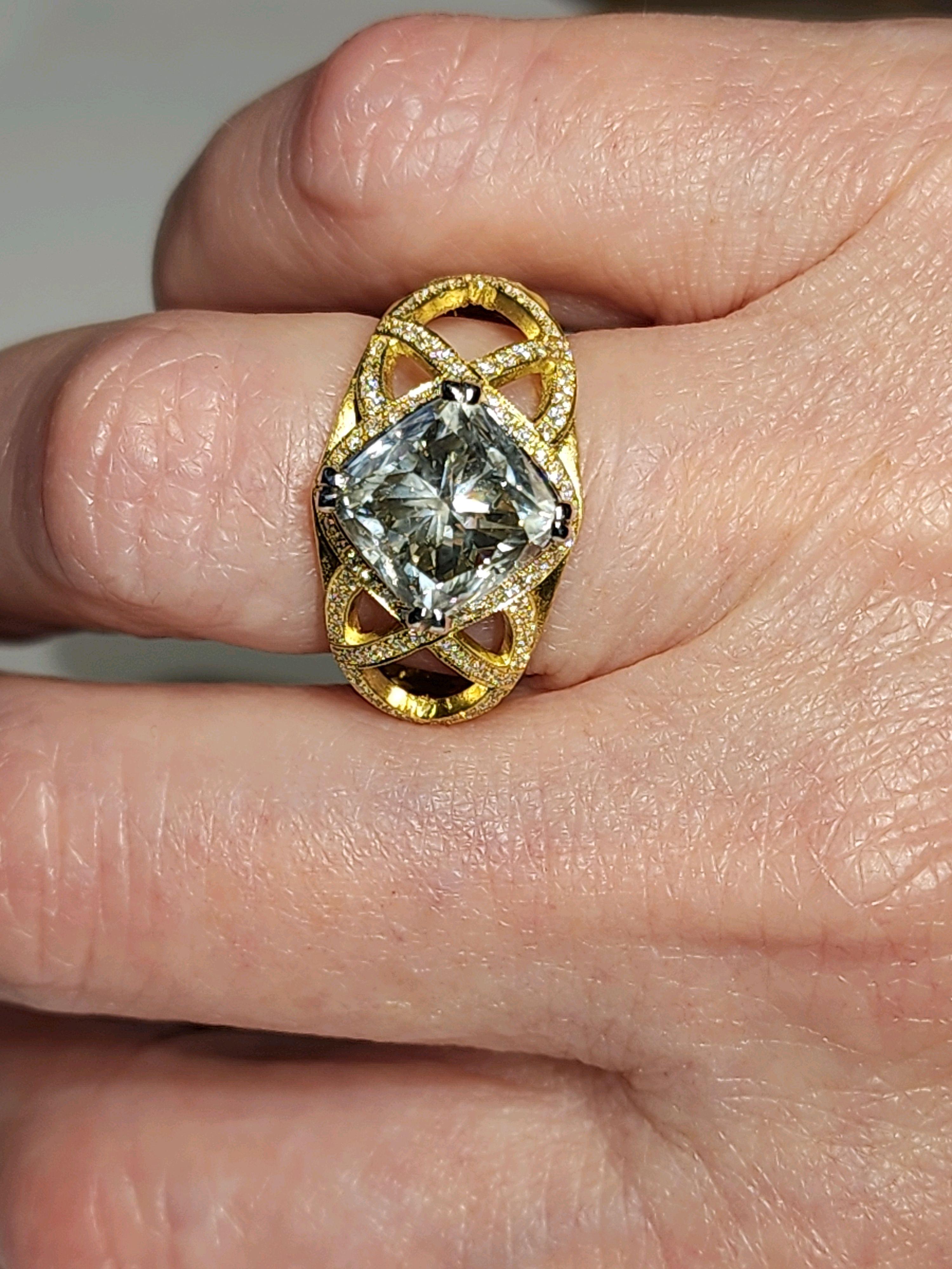 A stunning 5.12 carat diamond ring set in 18kt matte yellow gold. The Radiant Cushion-cut diamond is 4.49 carats and elicits a mirror like effect to light that is refracted within, and is complemented by the warmth of yellow gold. The center Diamond
