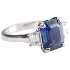 5.12 Carat Natural Emerald Cut Vivid Blue Sapphire and Diamond Three-Stone Ring