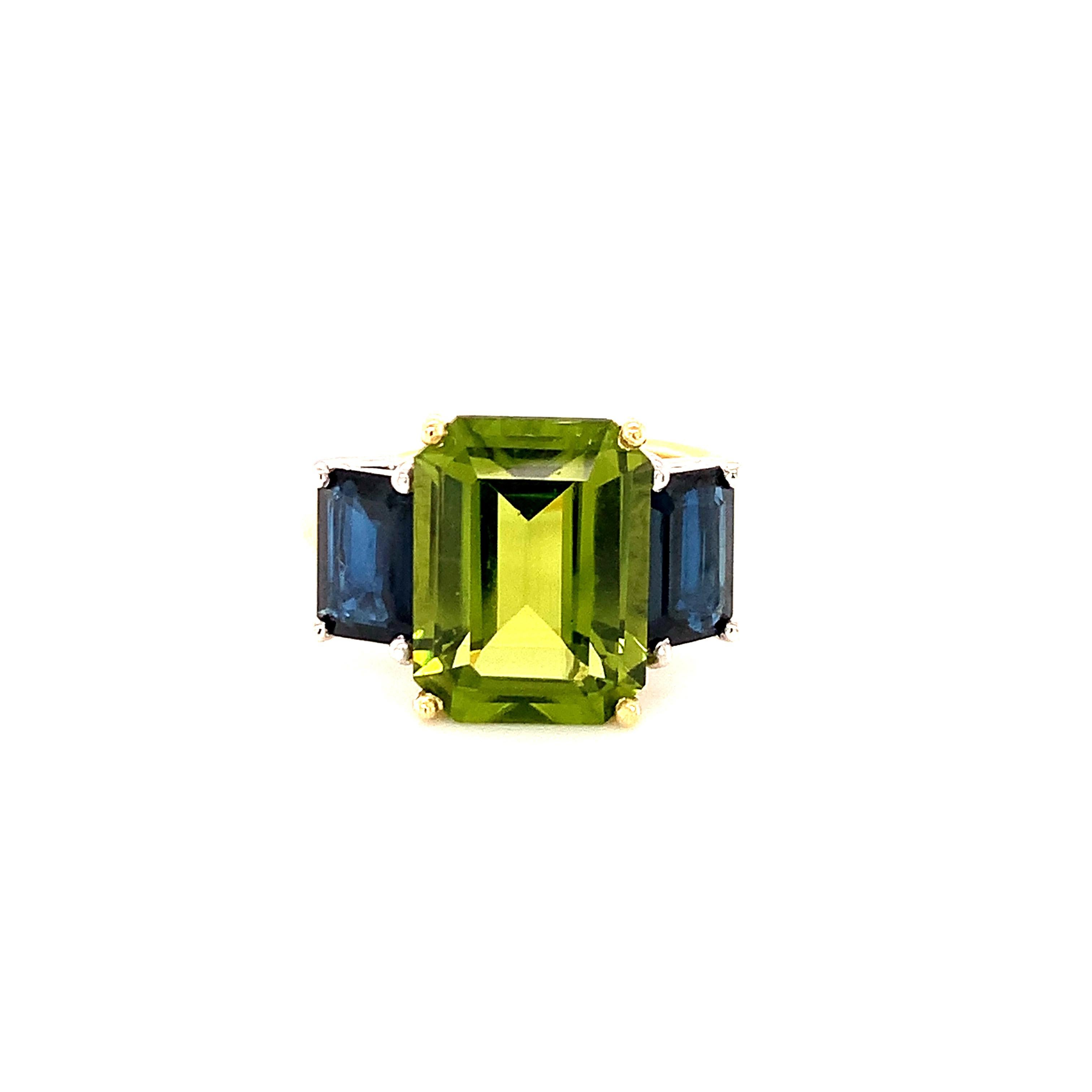A beautiful pairing of bright colors and sleek shapes form this modern version of a classic 3-stone ring. This stylish ring features a gorgeous, 5.12 carat emerald-cut peridot flanked on either side by emerald-cut rich blue sapphires. The peridot