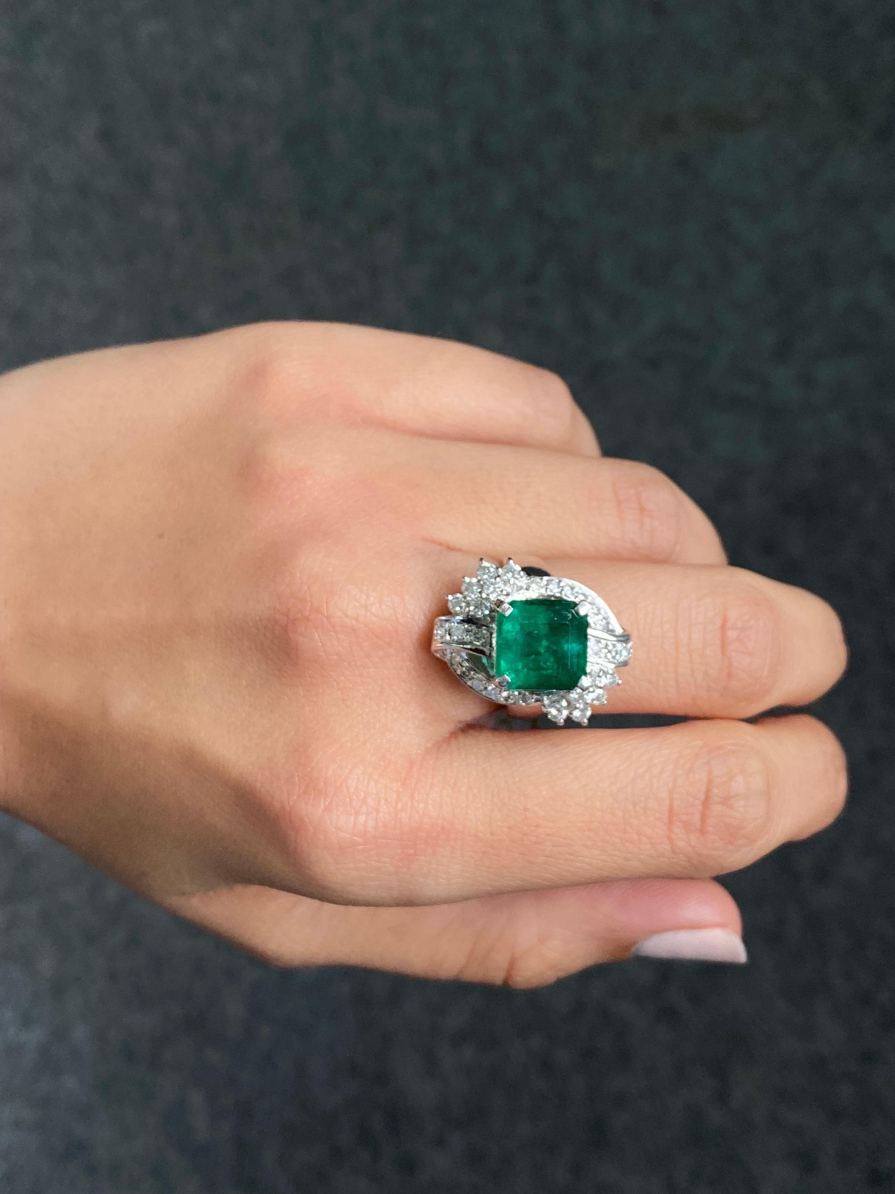 A statement cocktail ring, with a 5.13 carat Zambian Emerald center stone, and 0.75 carat White Diamond all set in Platinum. The center stone is transparent, with a few naturally occurring inclusions - the stone has an ideal vivid green color, and