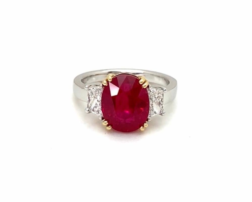 Cette spectaculaire bague de fiançailles à trois pierres est ornée d'un magnifique rubis rouge pur de 5,12 carats. Cette pierre précieuse de classe mondiale est un ovale magnifiquement symétrique, d'une couleur idéale et d'une brillance et d'une