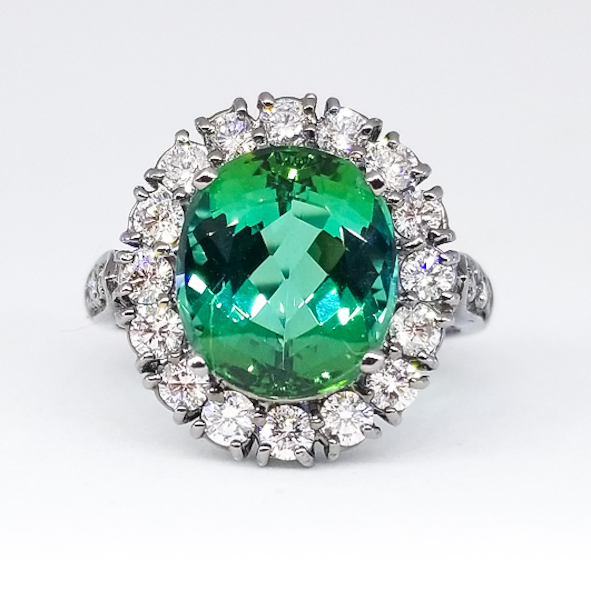 A 5.14 Carat Natural Fancy Mint Green Tourmaline of Gem Clarity and Exceptional Cutting is the centerpiece of this ring. The brilliant cut center stone is prong set and is surrounded by White Round Brilliant Diamonds of G Color and Vs Clarity and a