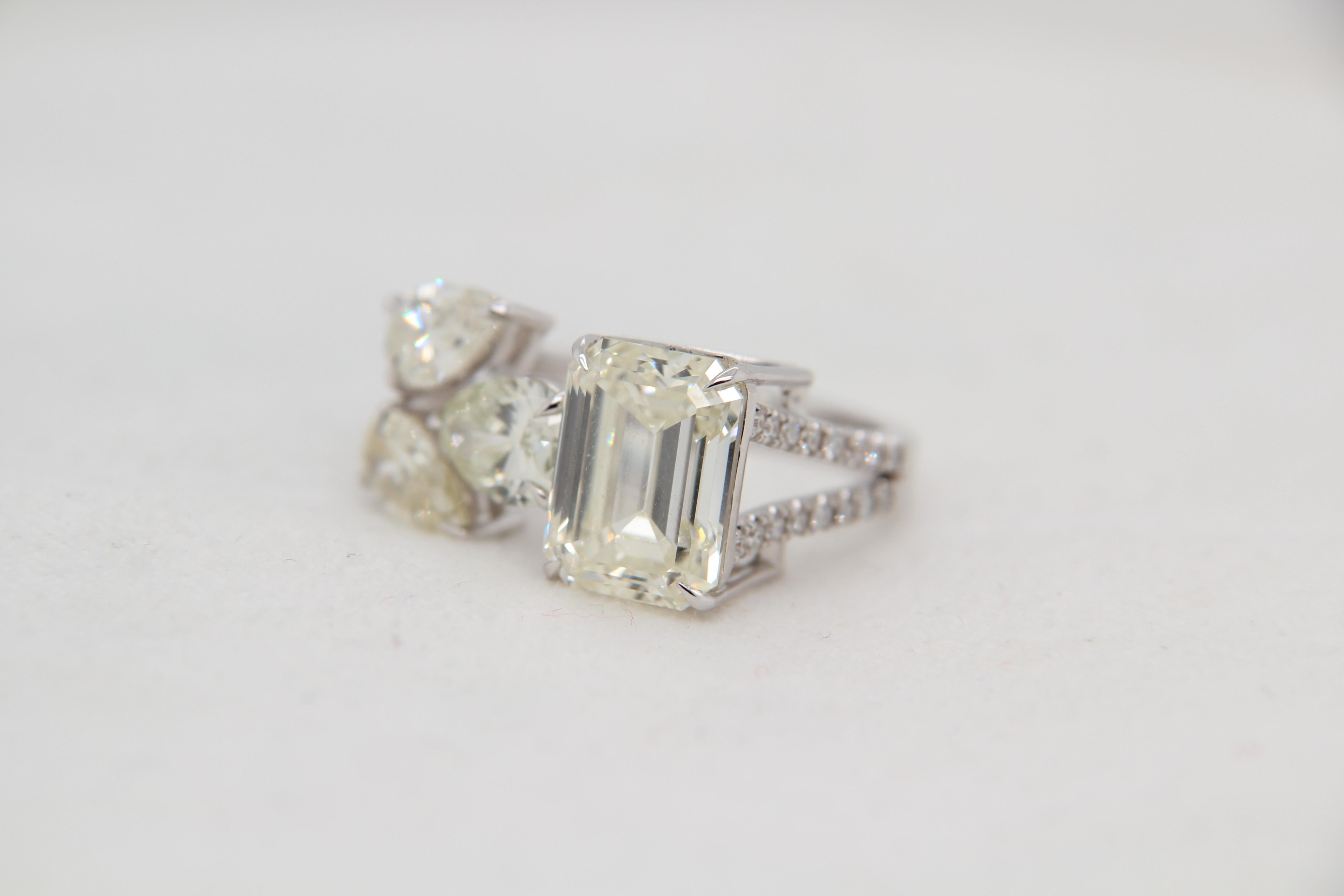 A new emerald cut and pear shape diamond ring. The emerald cut diamond weighs 5.18 carat and the 3 pear shapes weigh 2.38 carat. There are round diamonds along the top half of the band weighing at 0.24 carat. The total weight of the ring is 7.30
