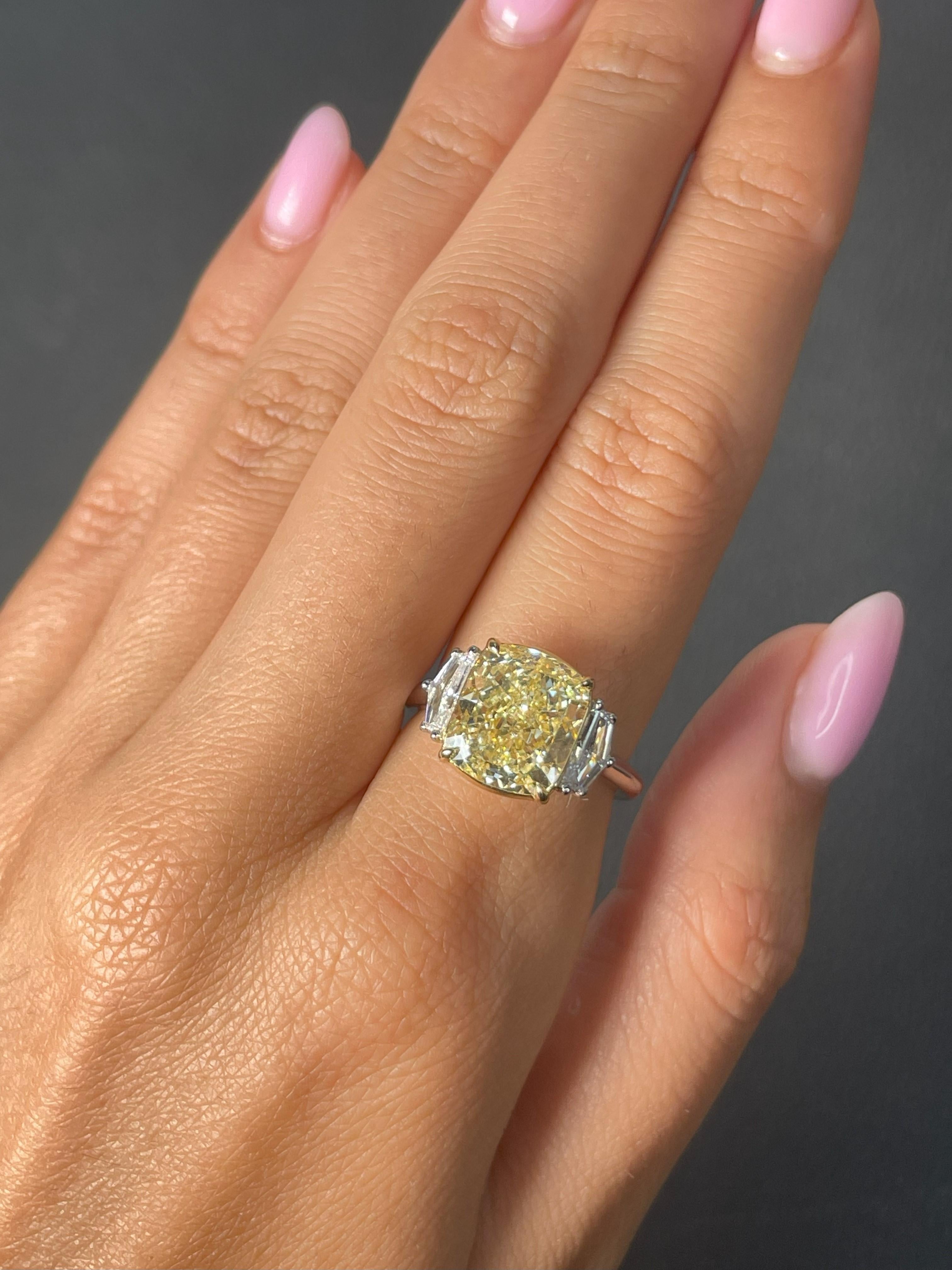 Exquisite Three-Stone Engagement Ring featuring a 5.19 carat Fancy Light Yellow, Cushion-cut diamond. certified by GIA as VS1 in clarity. The center diamond is elegantly accompanied by two Epaulet-cut diamonds with a combined weight of 0.57 carats,